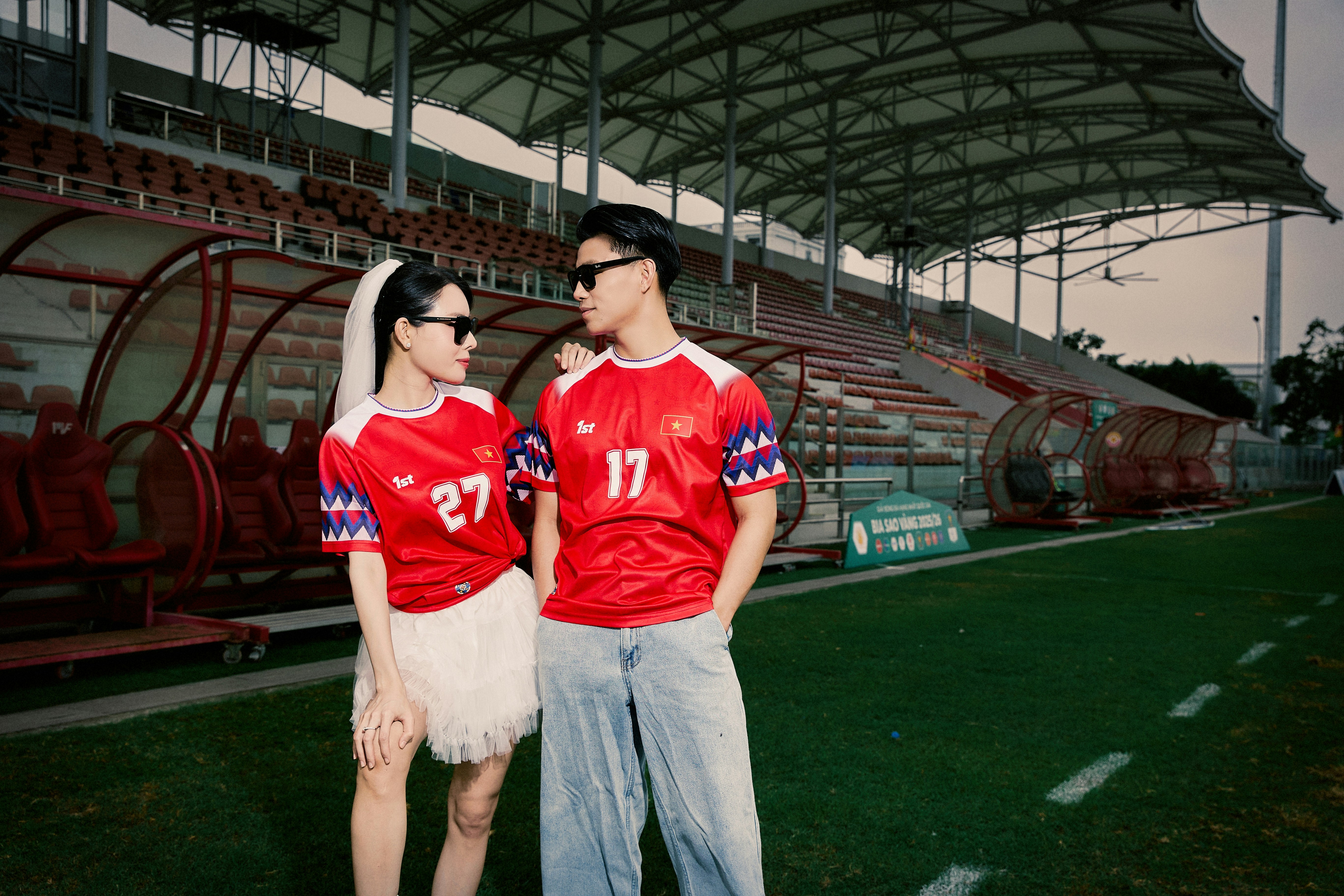 Couple in red soccer jerseys standing on a stadium field