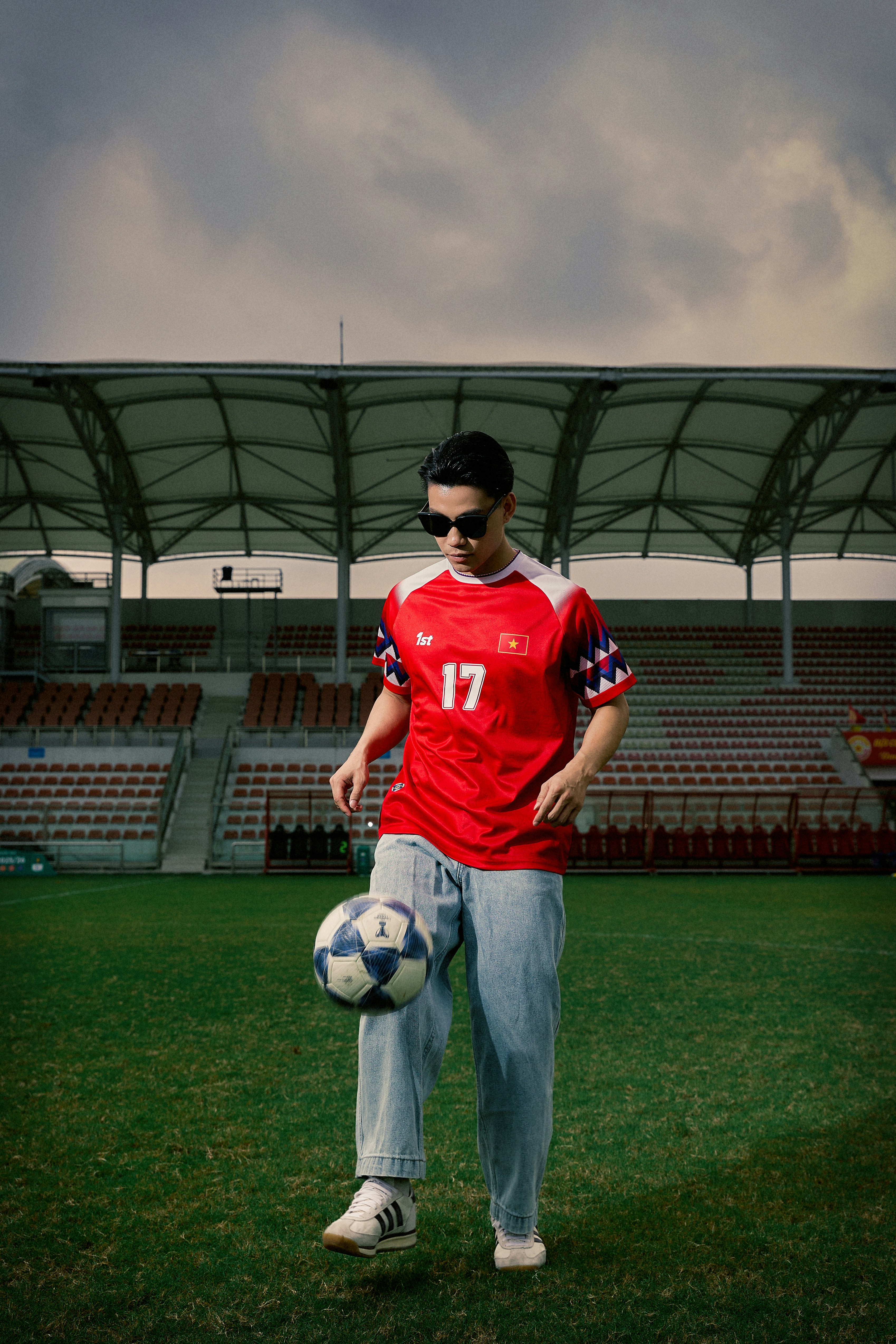 Pria berjersey merah menyulap bola sepak di lapangan stadion.