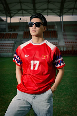 Man in red vietnamese soccer jersey stands on a field