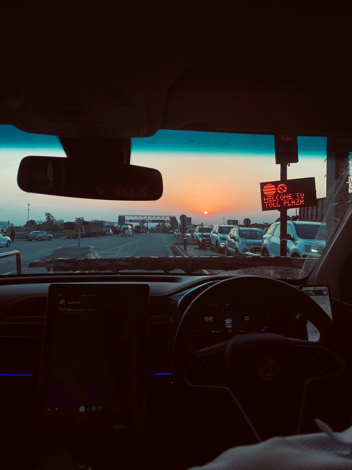 Sunset over a toll plaza seen from inside a car
