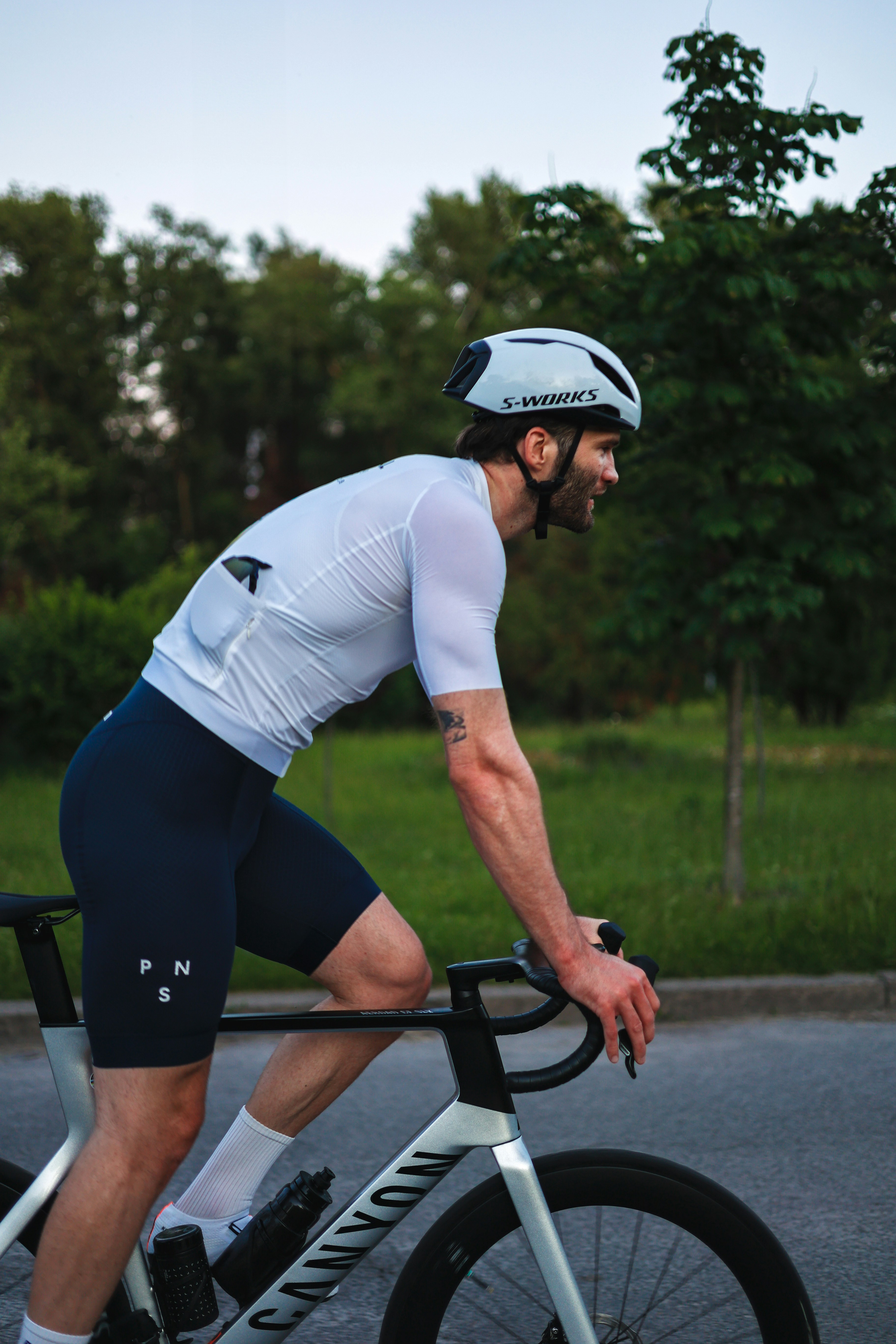 A man in a white jersey and helmet cycles outdoors