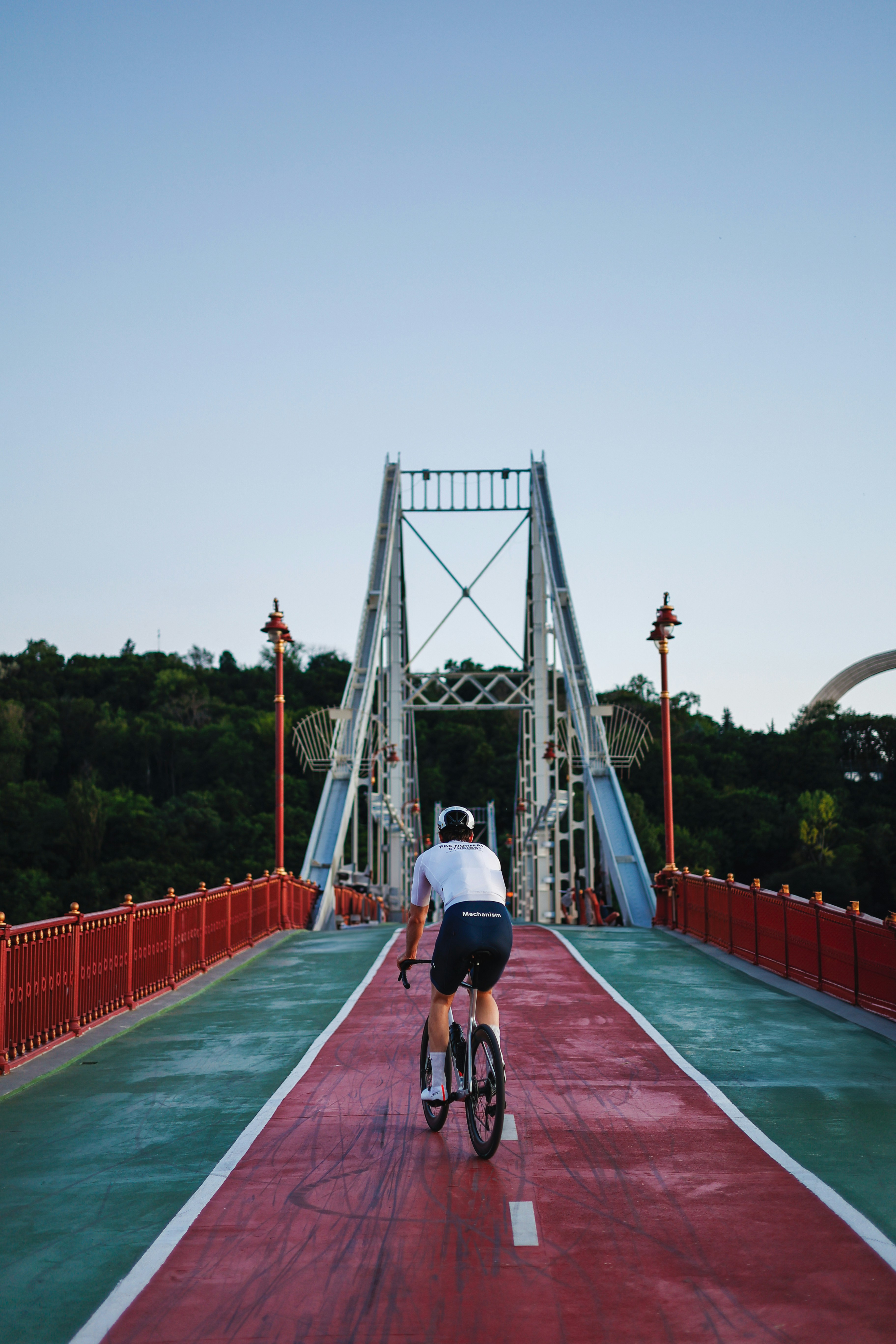A person cycles on a red path over a bridge