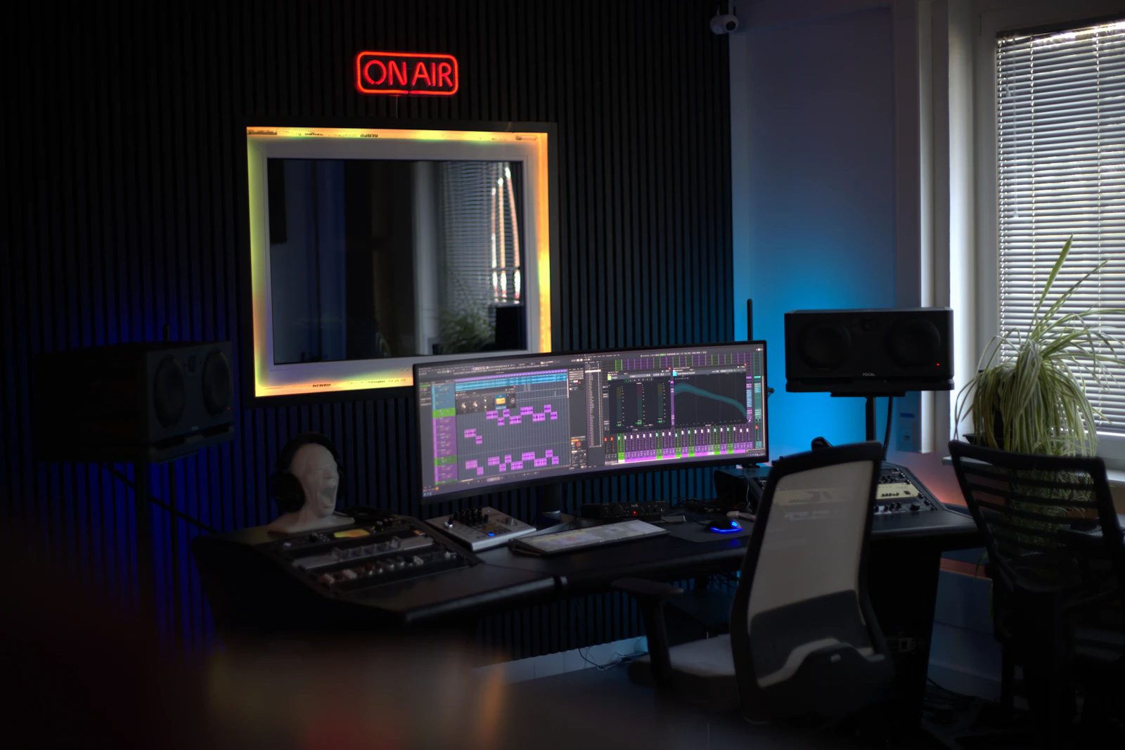Radio studio with an illuminated on-air sign, computer displays, and mixing console