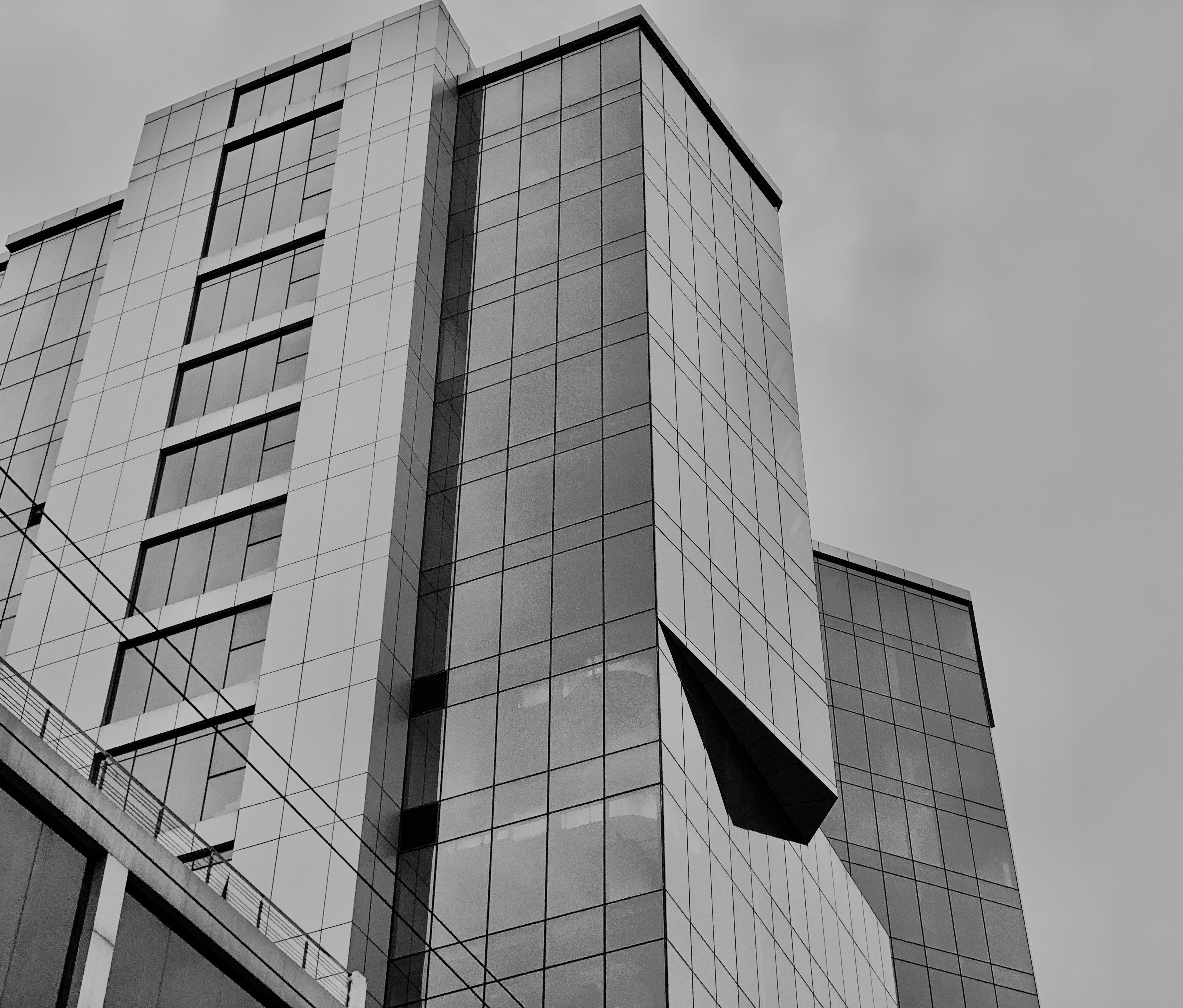 Tall modern glass skyscraper against a gray sky.