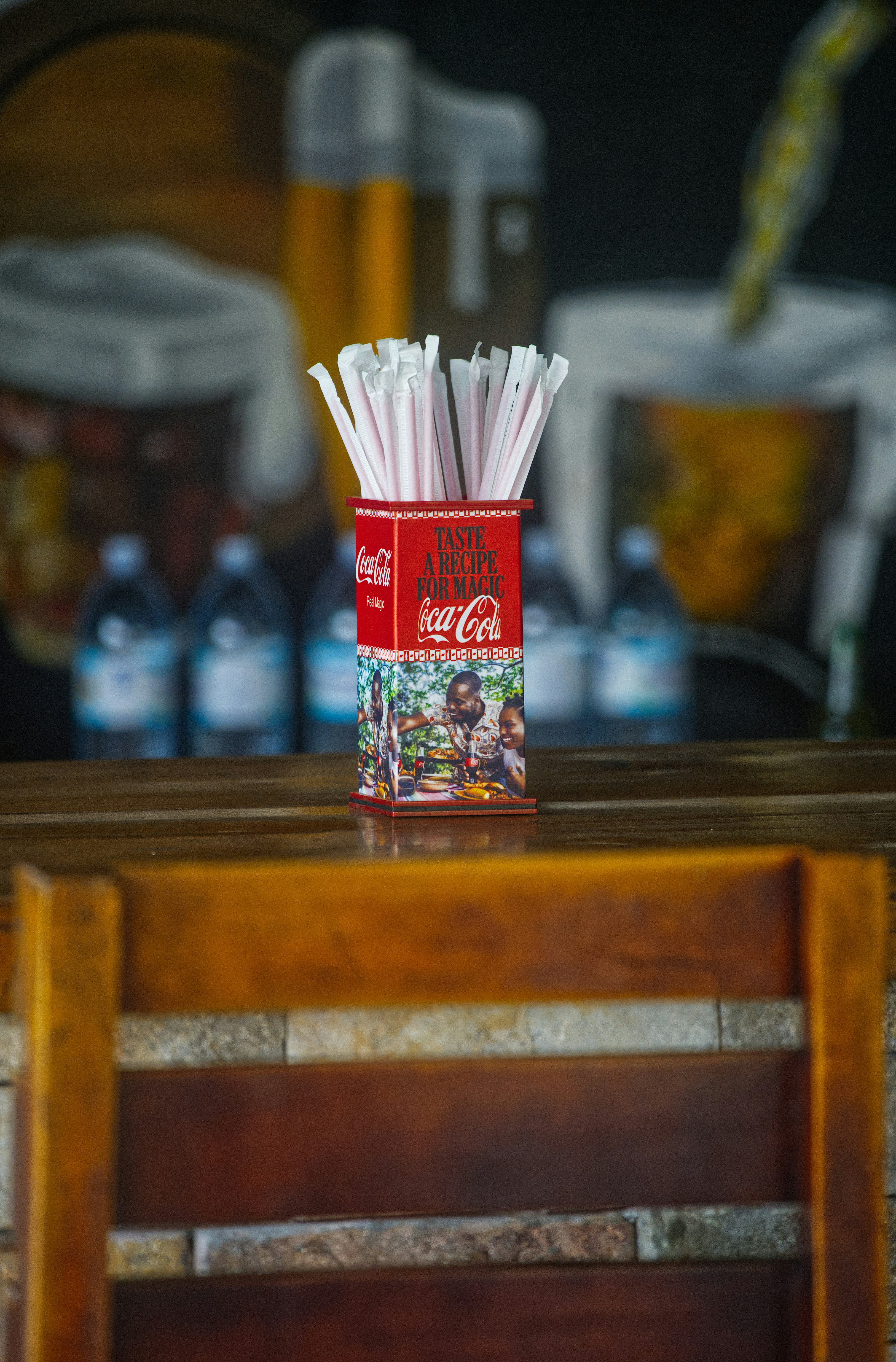Red coca-cola straw holder on a wooden counter.