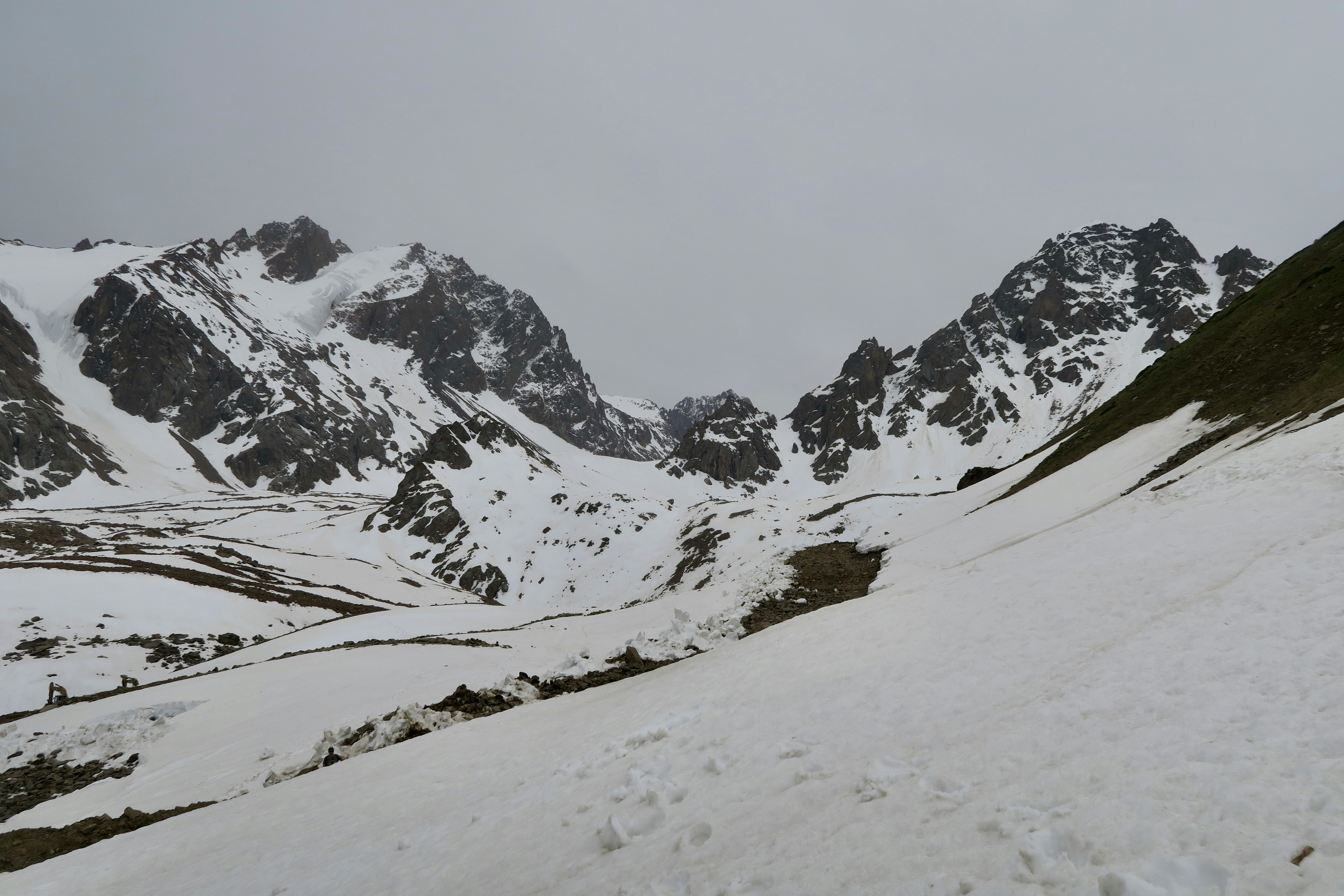 Snow-covered mountains and valleys under a cloudy sky.