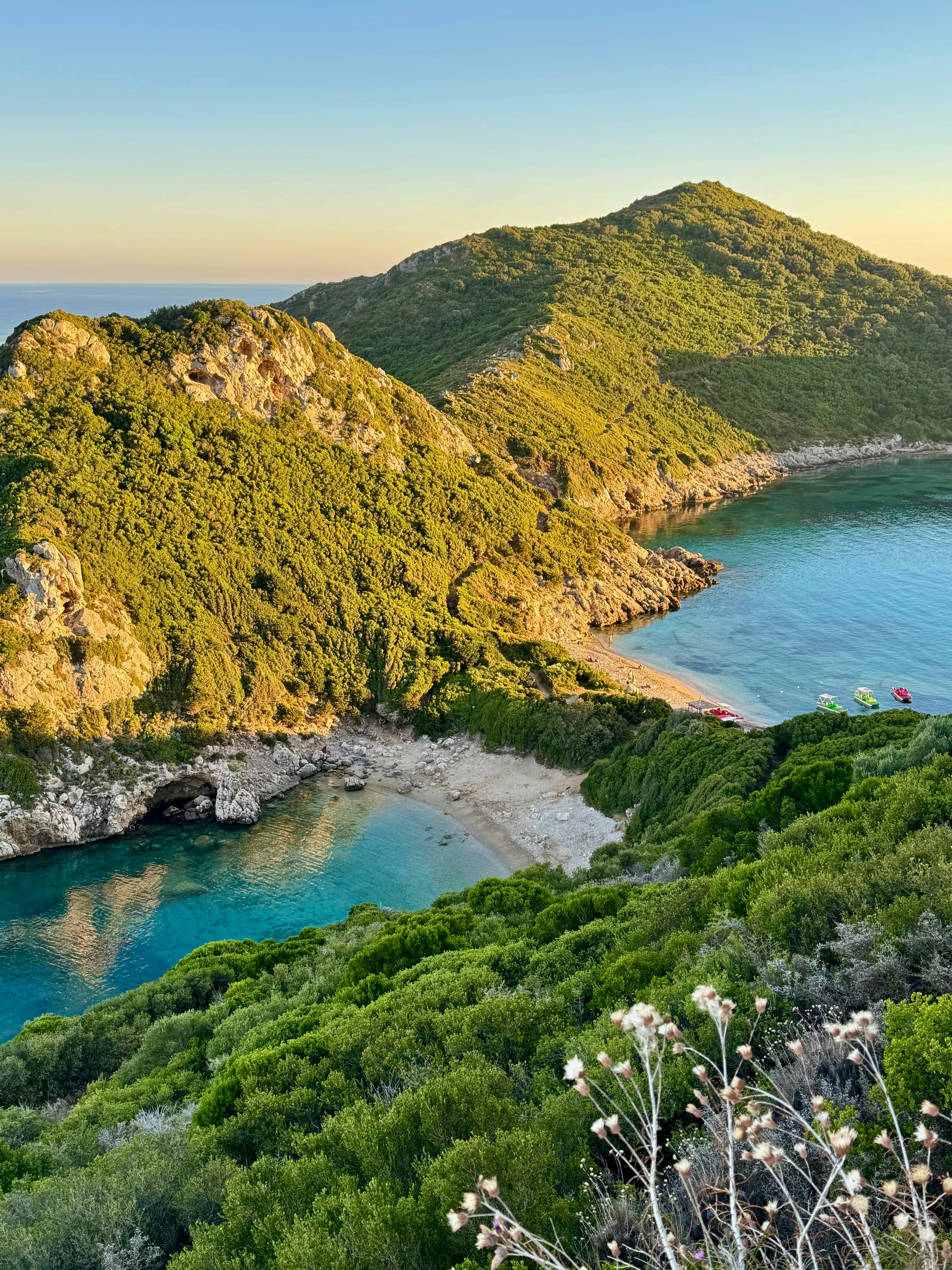 Lush green mountains overlook a tranquil bay and sandy beach