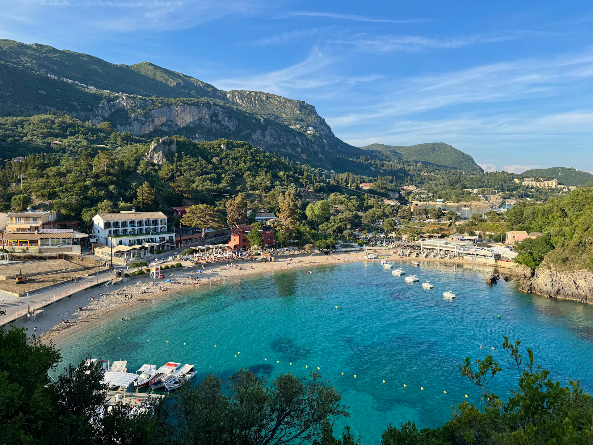 Beautiful bay with clear blue water, beach, buildings, and mountains