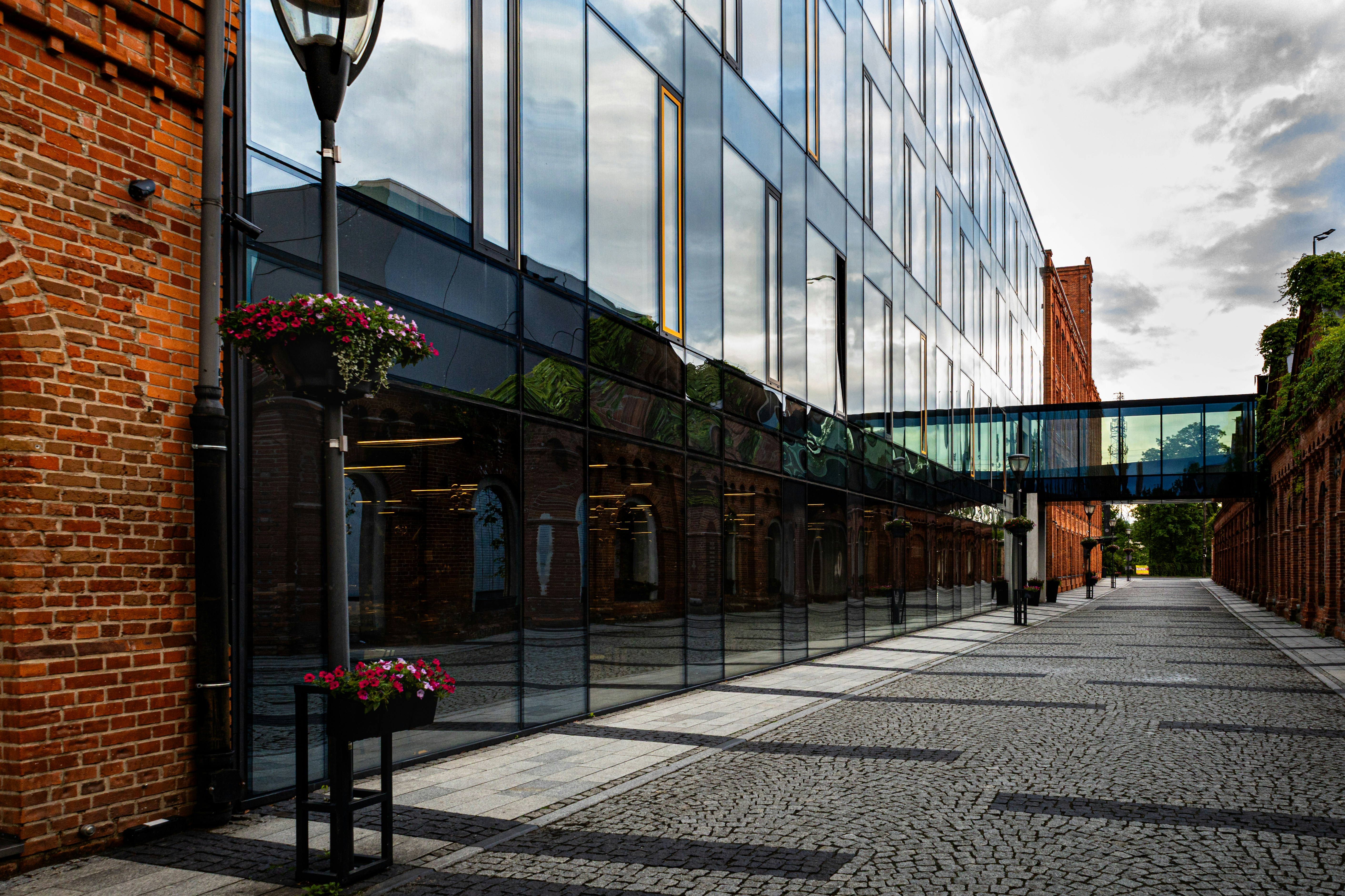 Modern glass building, brick wall, and cobblestone walkway.