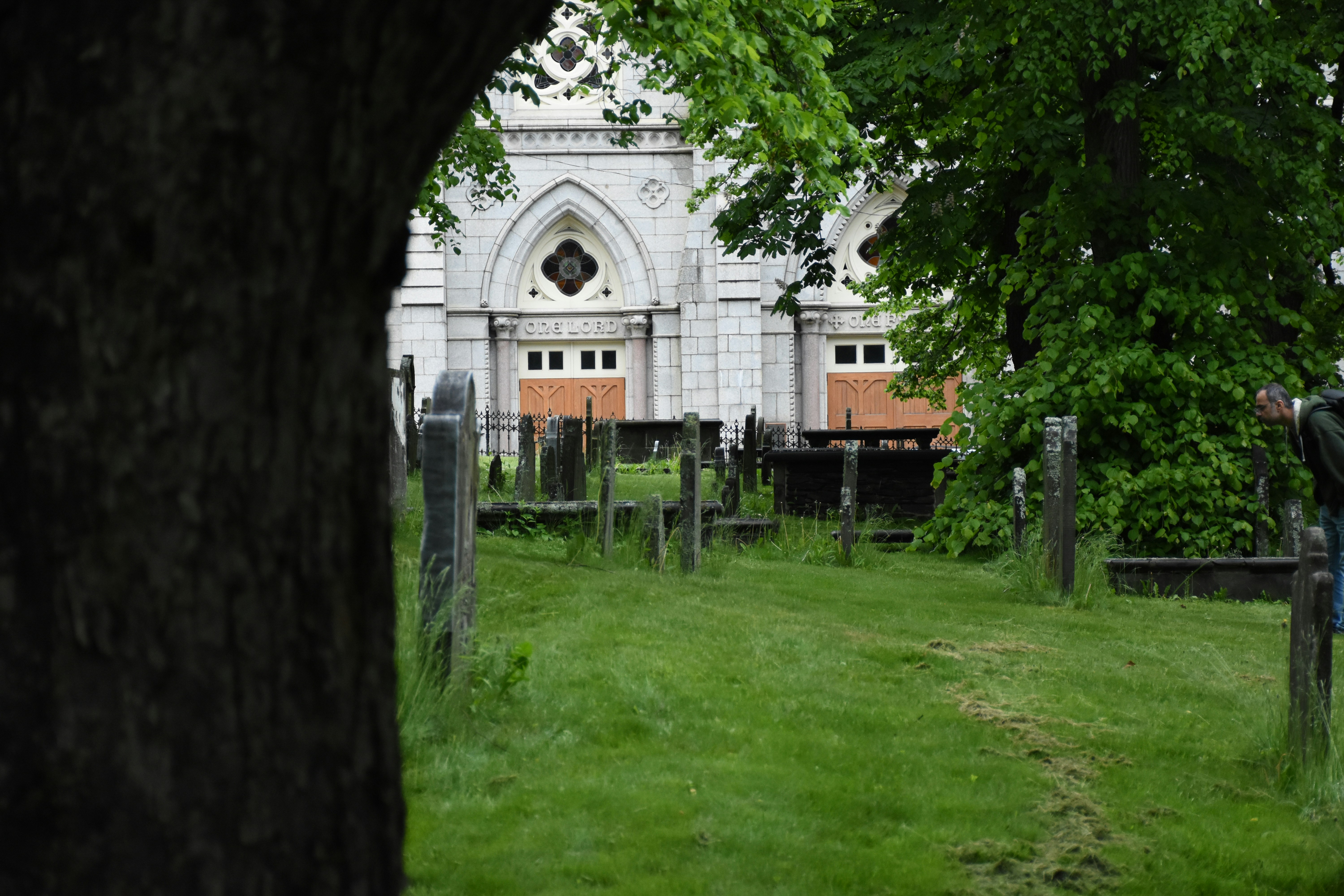 Old church seen through trees and gravestones.