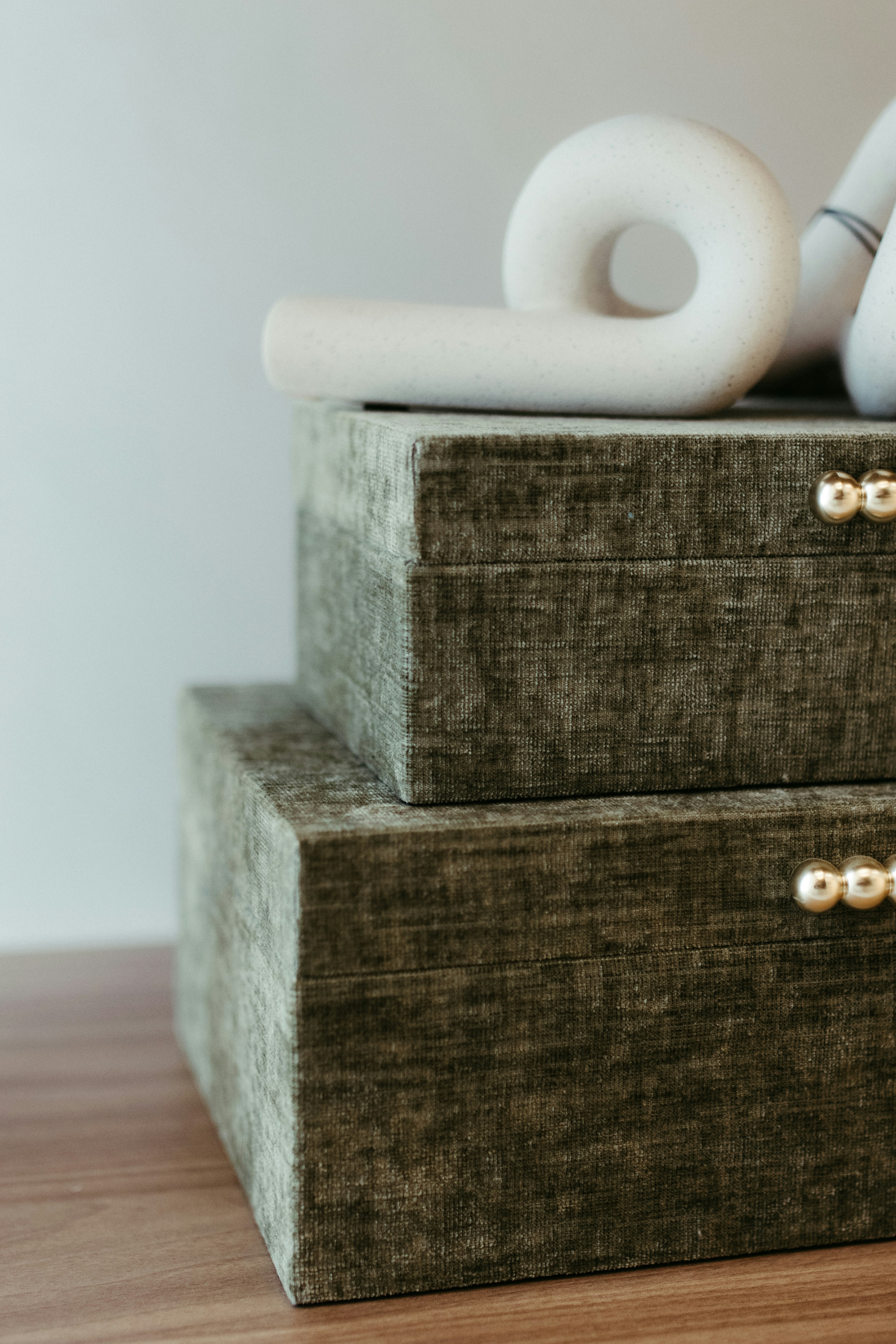 Two stacked green velvet boxes with a white abstract sculpture.