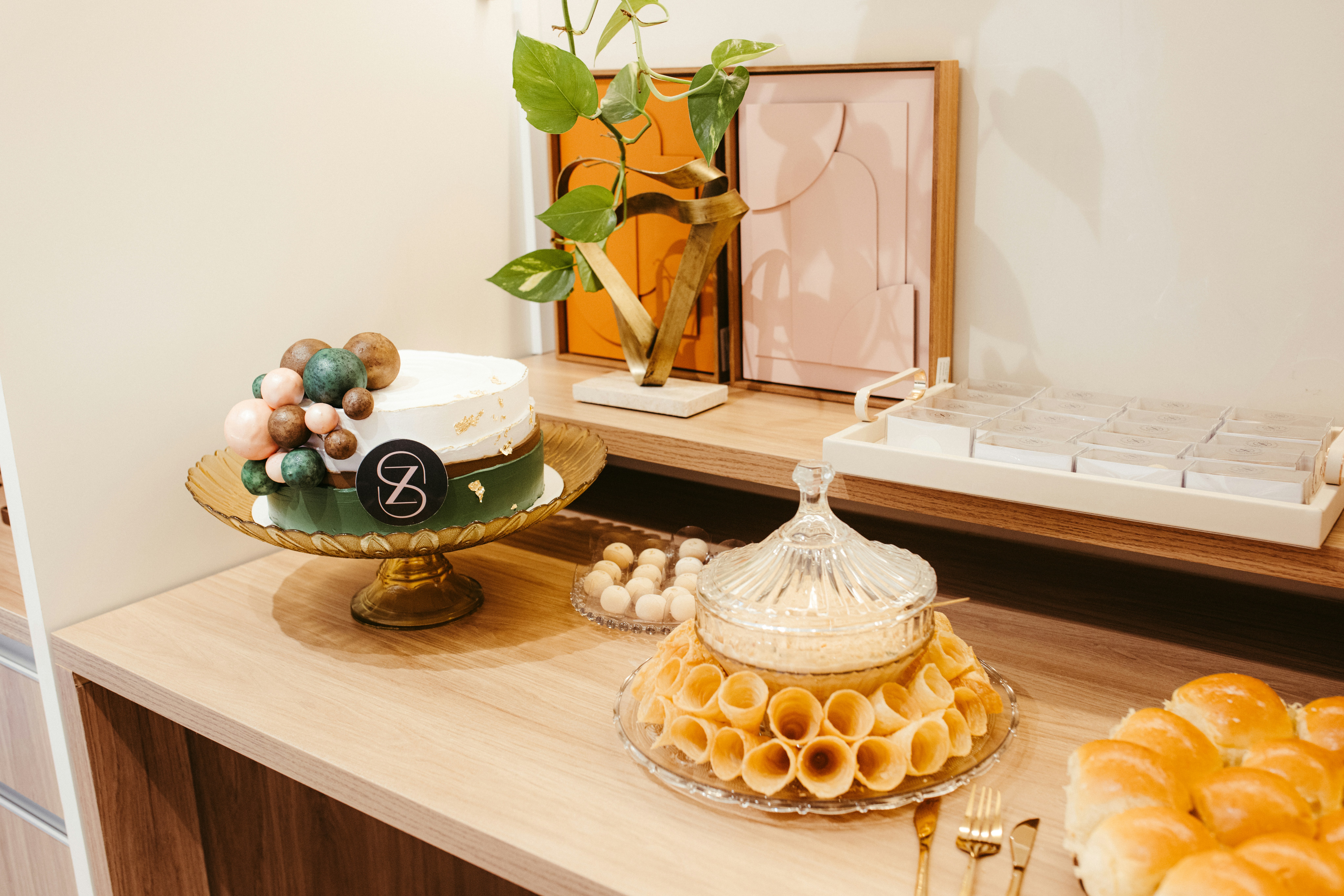 A birthday cake and pastries arranged on a wooden table.