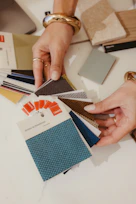 Hands choosing colorful fabric samples from a design palette.