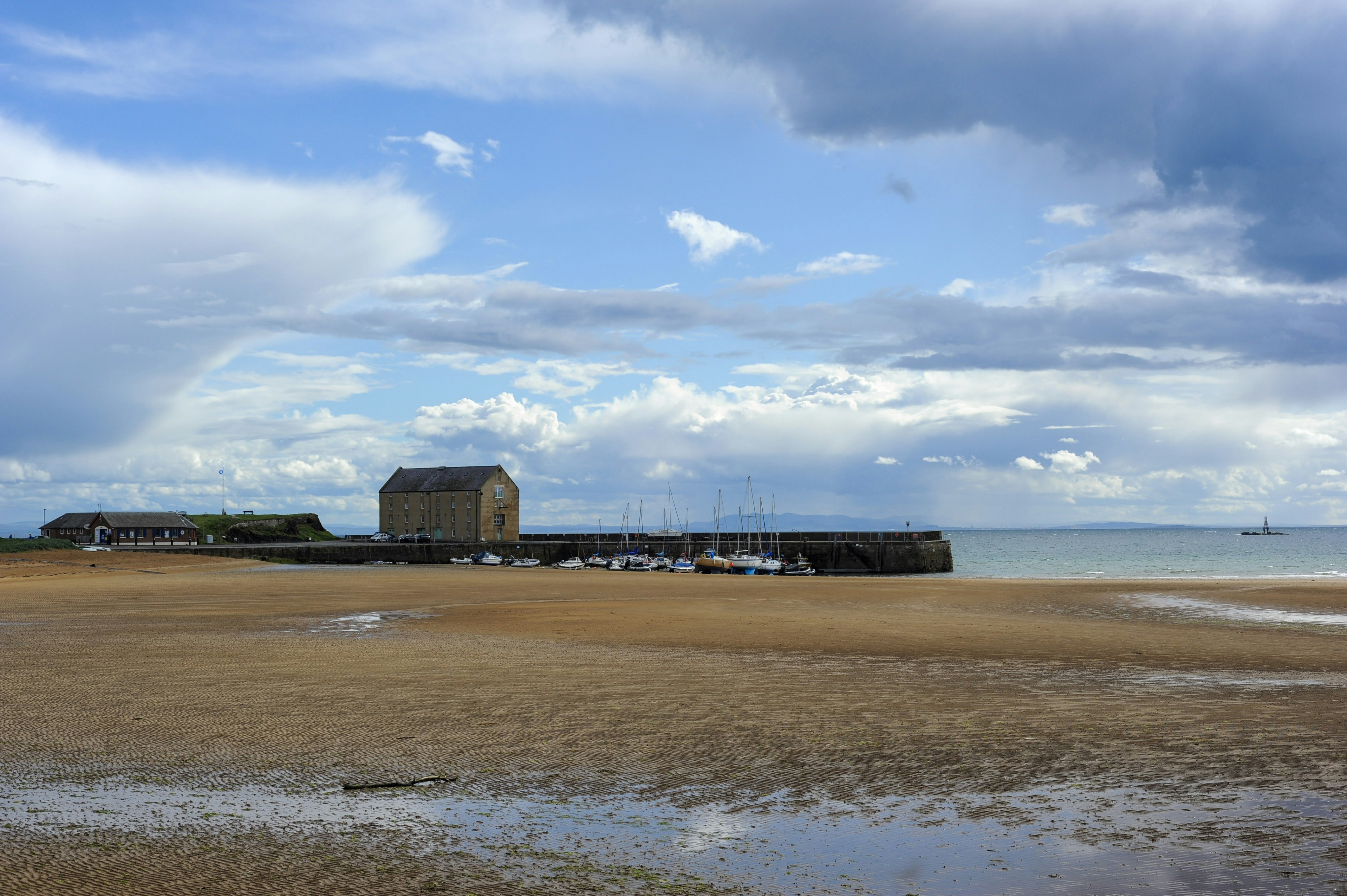 Boathouse and boats on sandy beach under cloudy sky