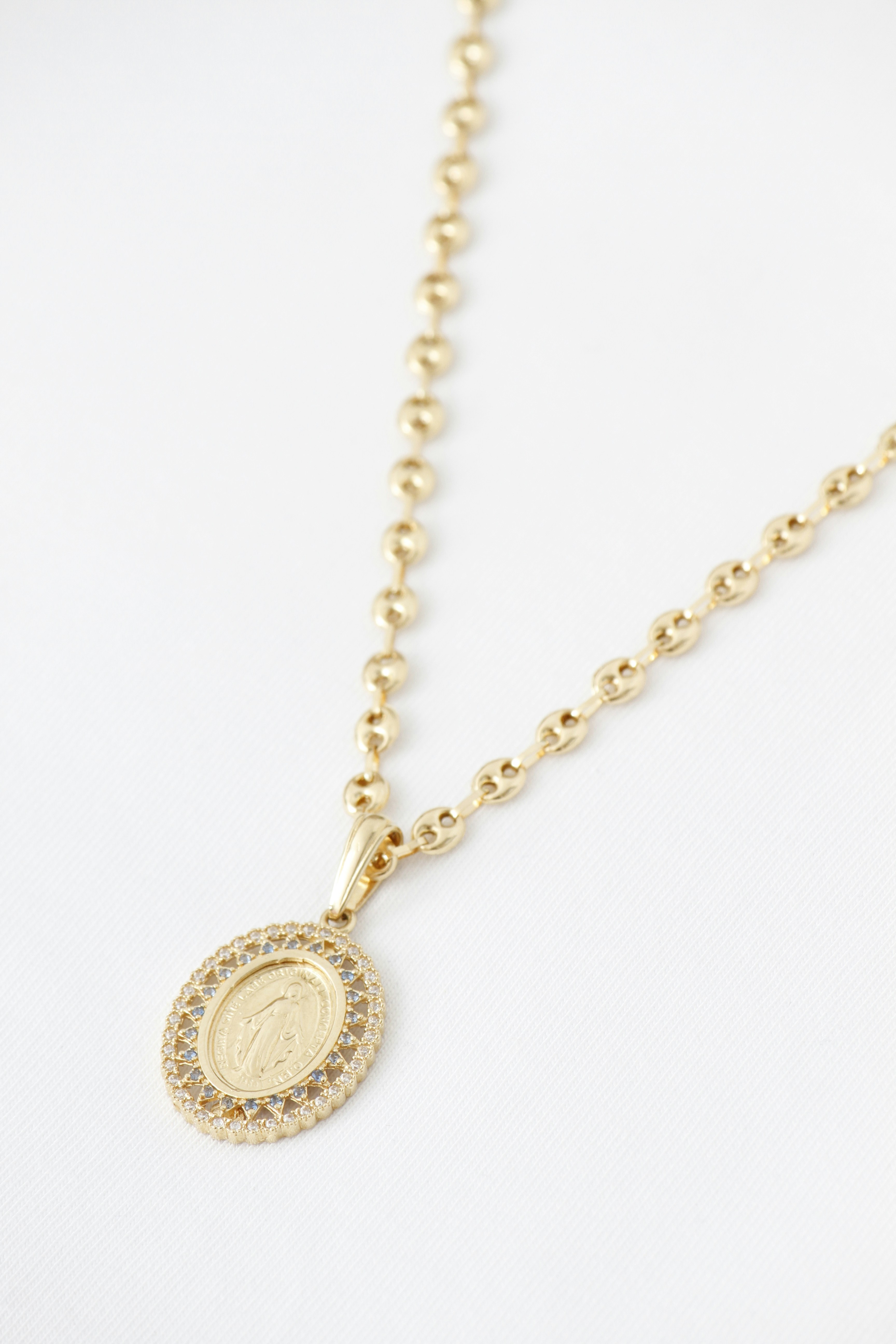 Gold necklace featuring an oval pendant with a religious figure.