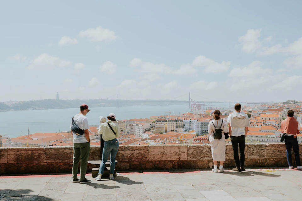 A sunny Atlantic beach below a Portuguese coastal town, with swimmers and rocks