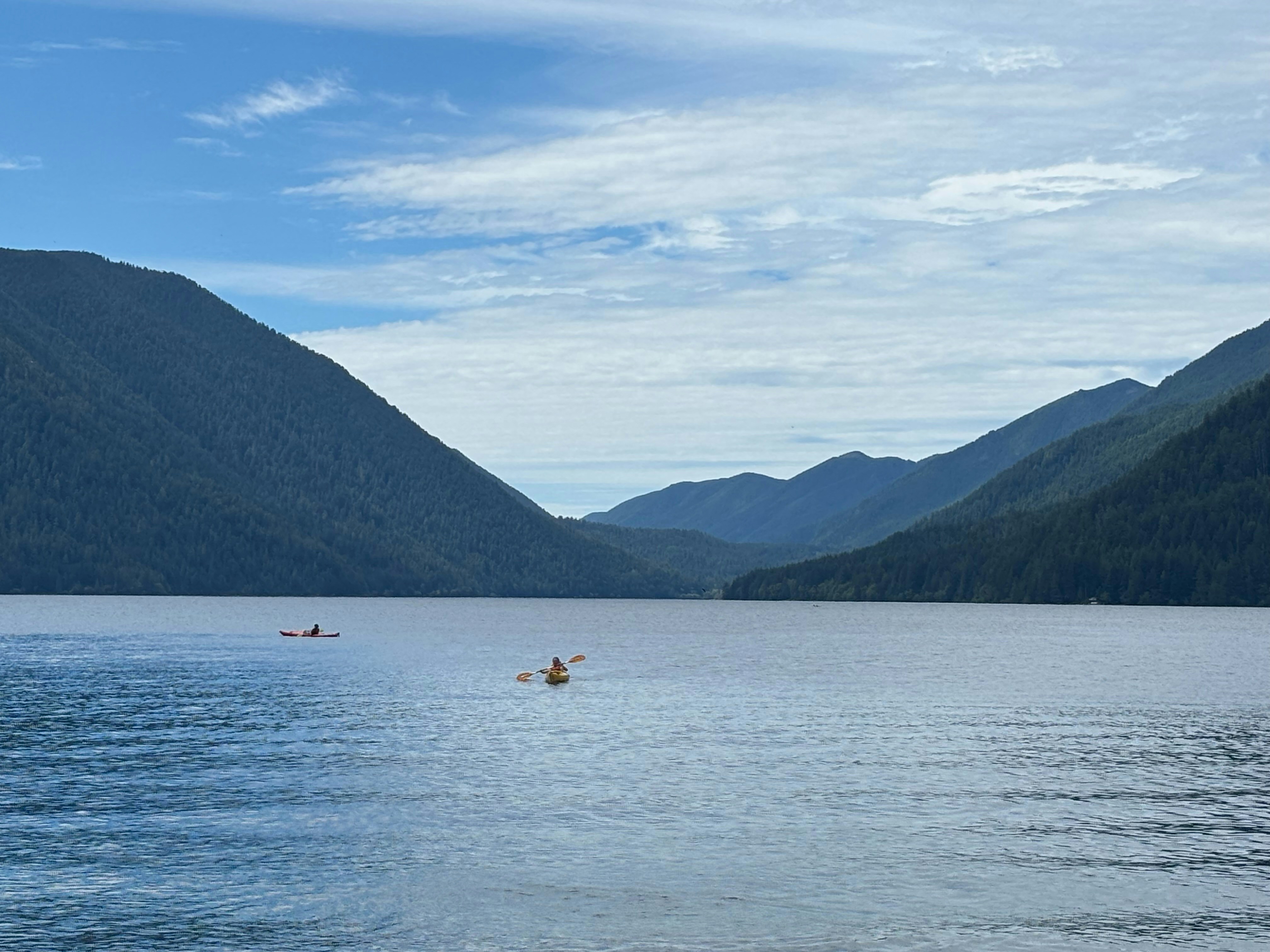 Kayaker di danau tenang yang dikelilingi oleh pegunungan.