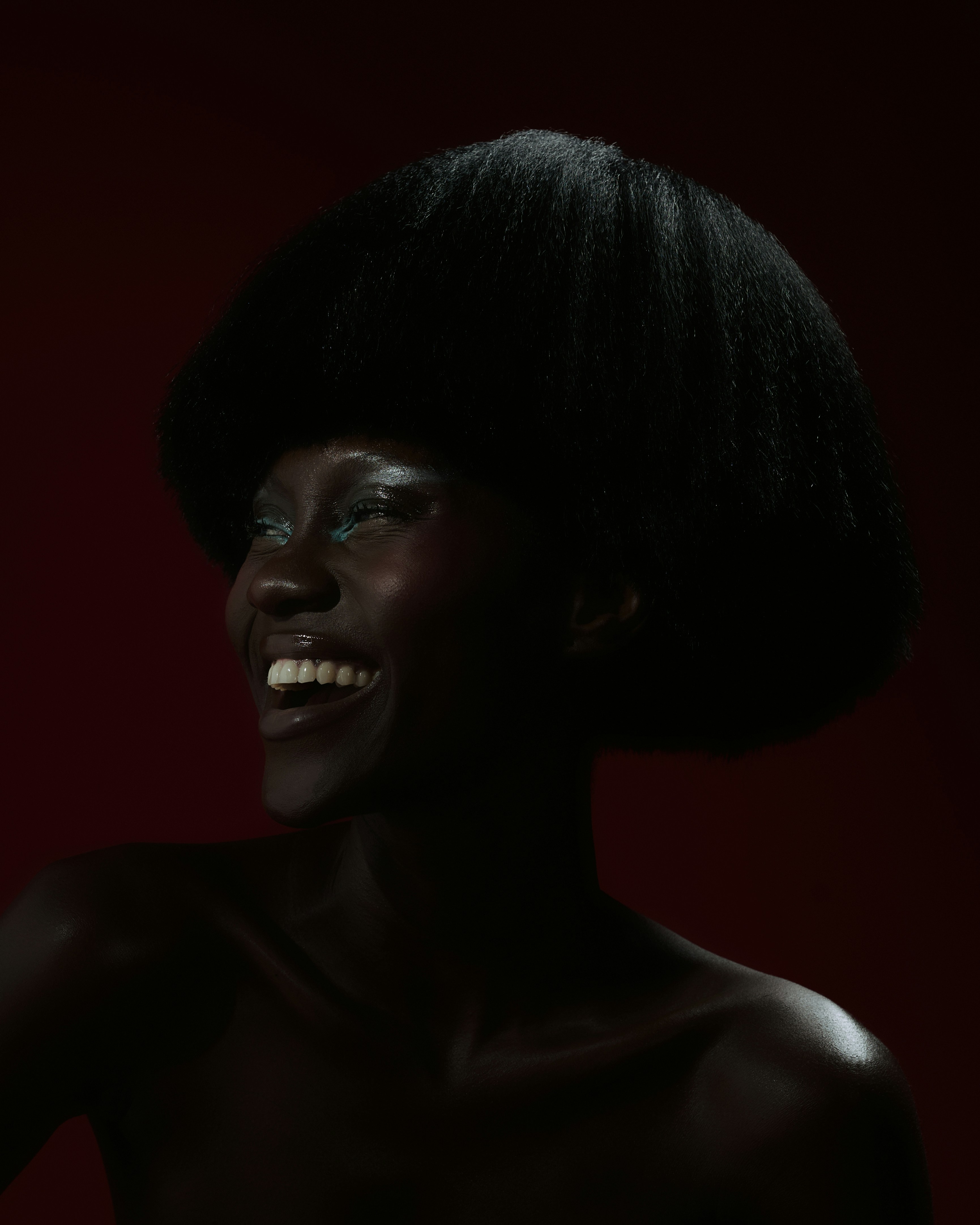 Smiling person with an afro hairstyle against a red background