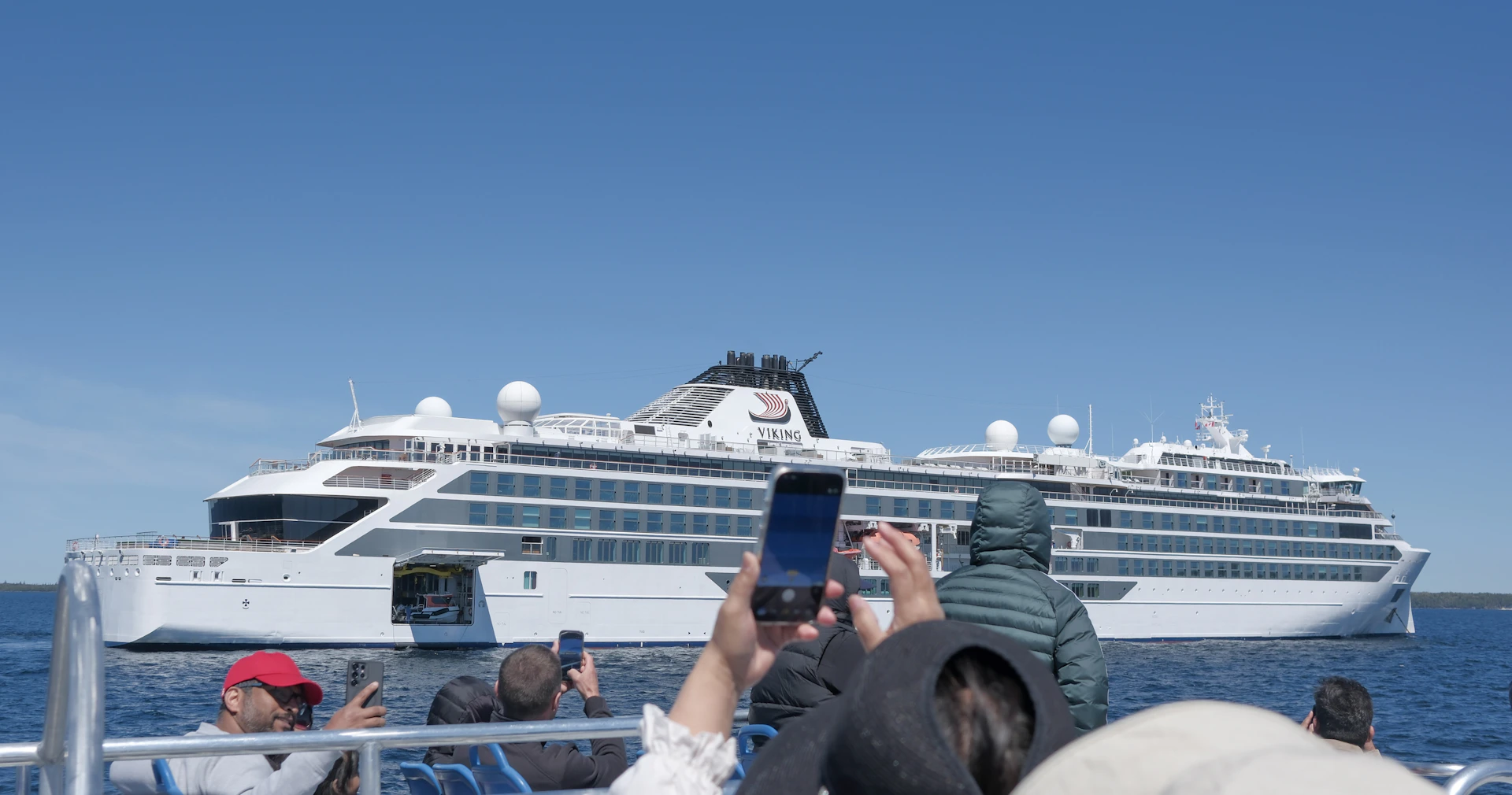 People on a boat photographing a large white cruise ship