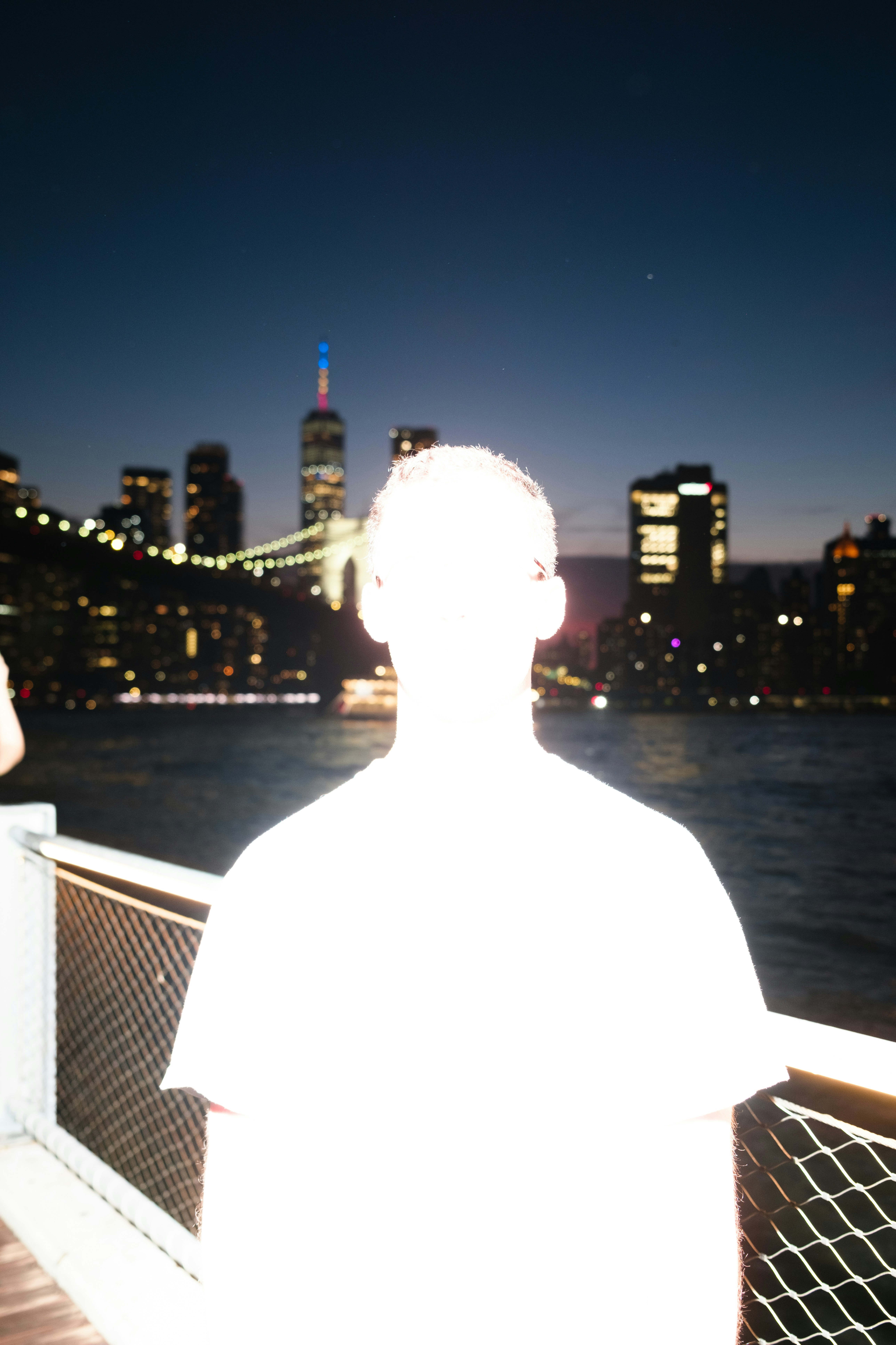 A person views a vibrant cityscape and bridge at night.