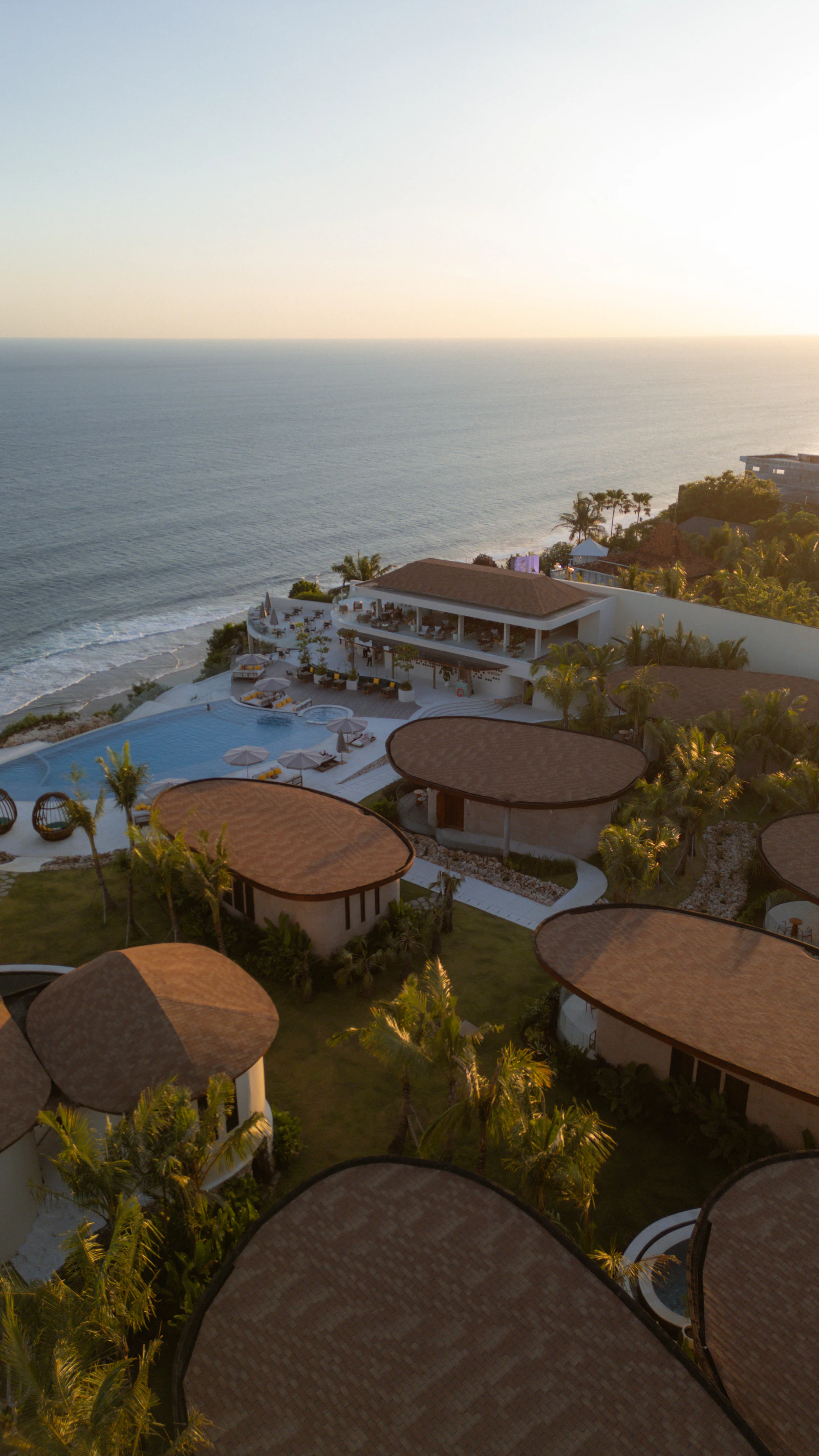 Beachfront resort villas and a pool overlooking the ocean at sunset
