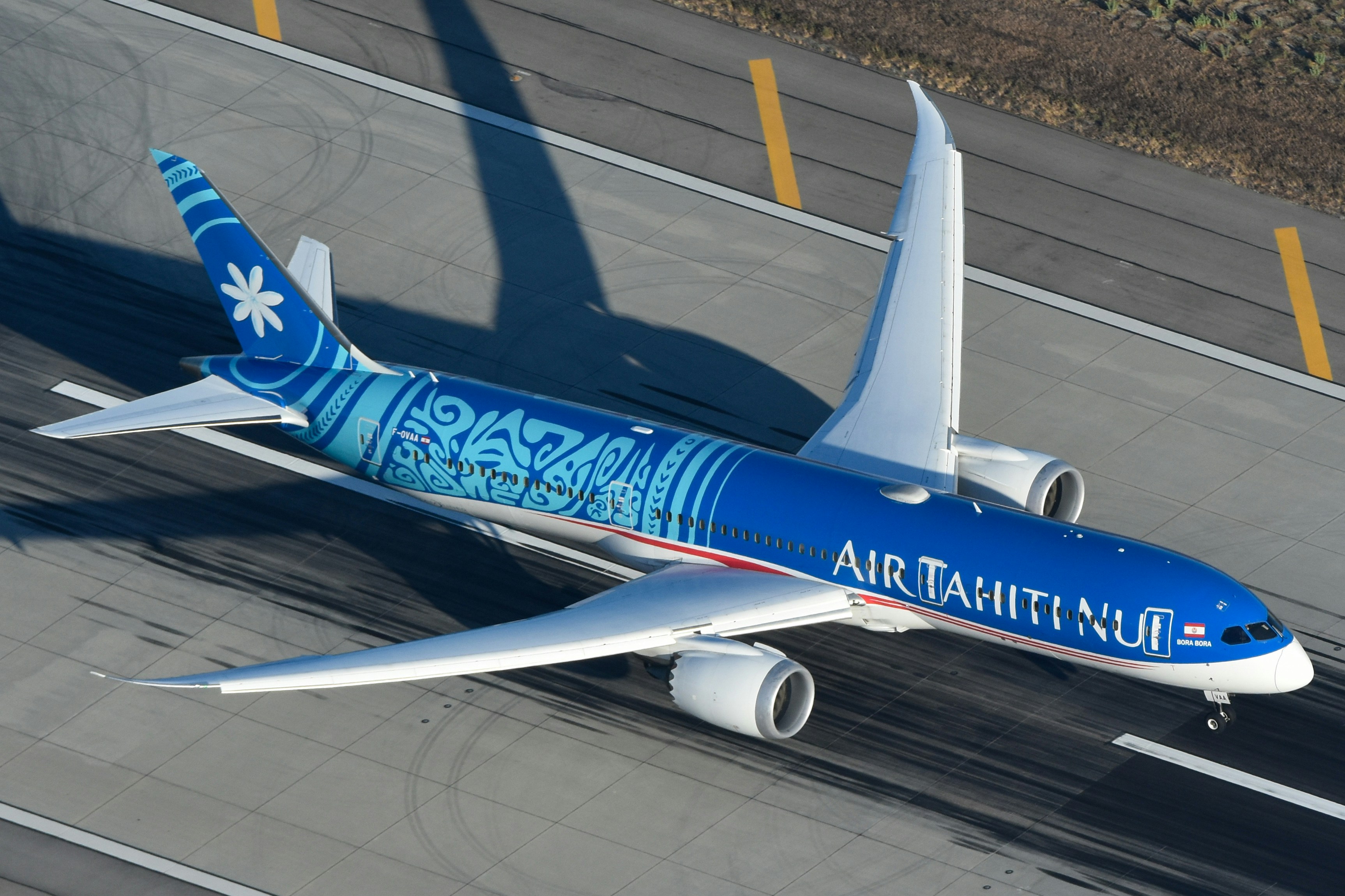 A blue air tahiti nui airplane on an airport runway.