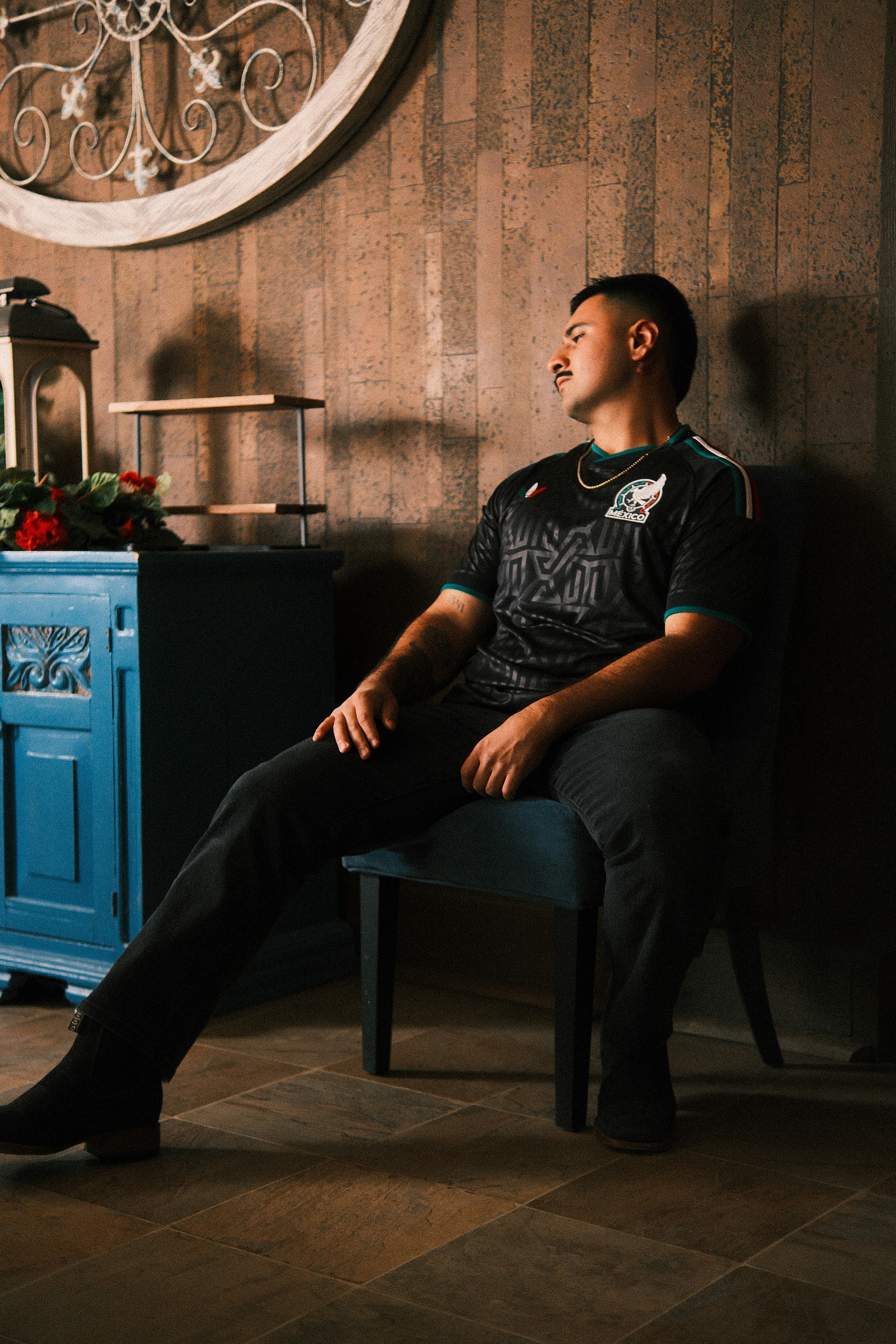 A man in a mexico jersey sits on a chair