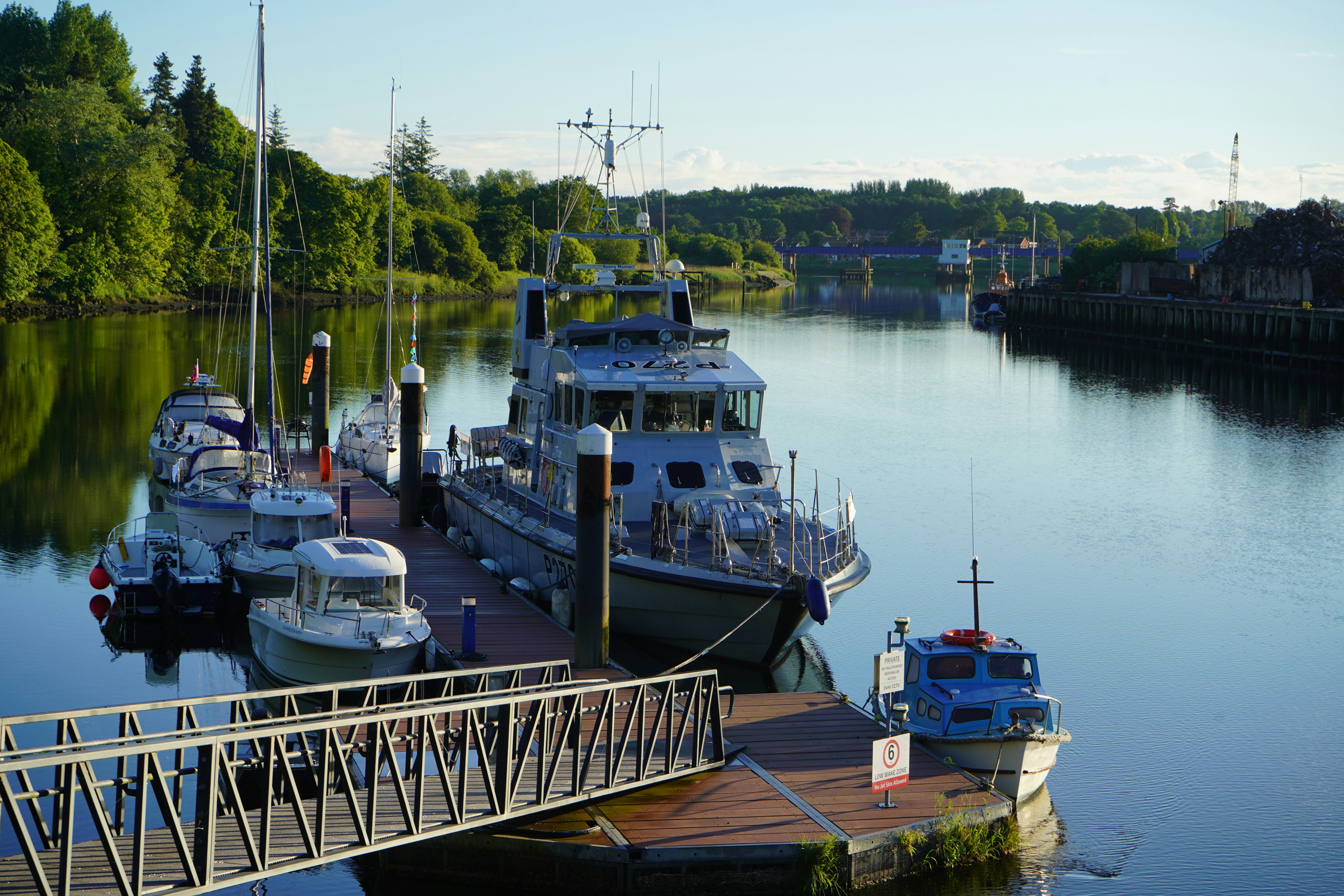 Boats docked on a calm river with green trees.