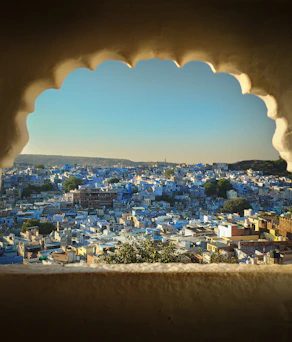 View of a blue city through an ornate arched window.