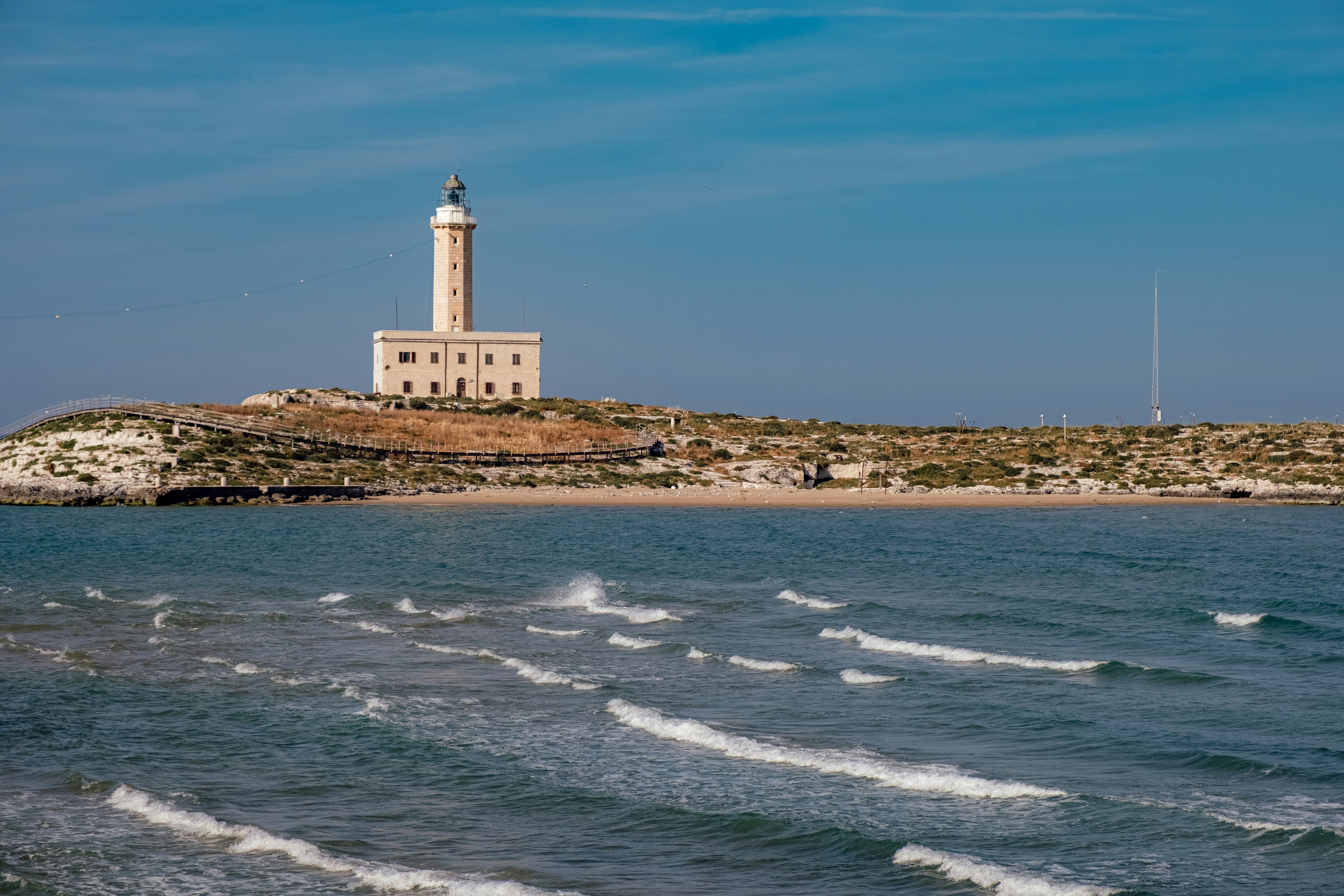 Lighthouse on a rocky coast with blue sky and ocean