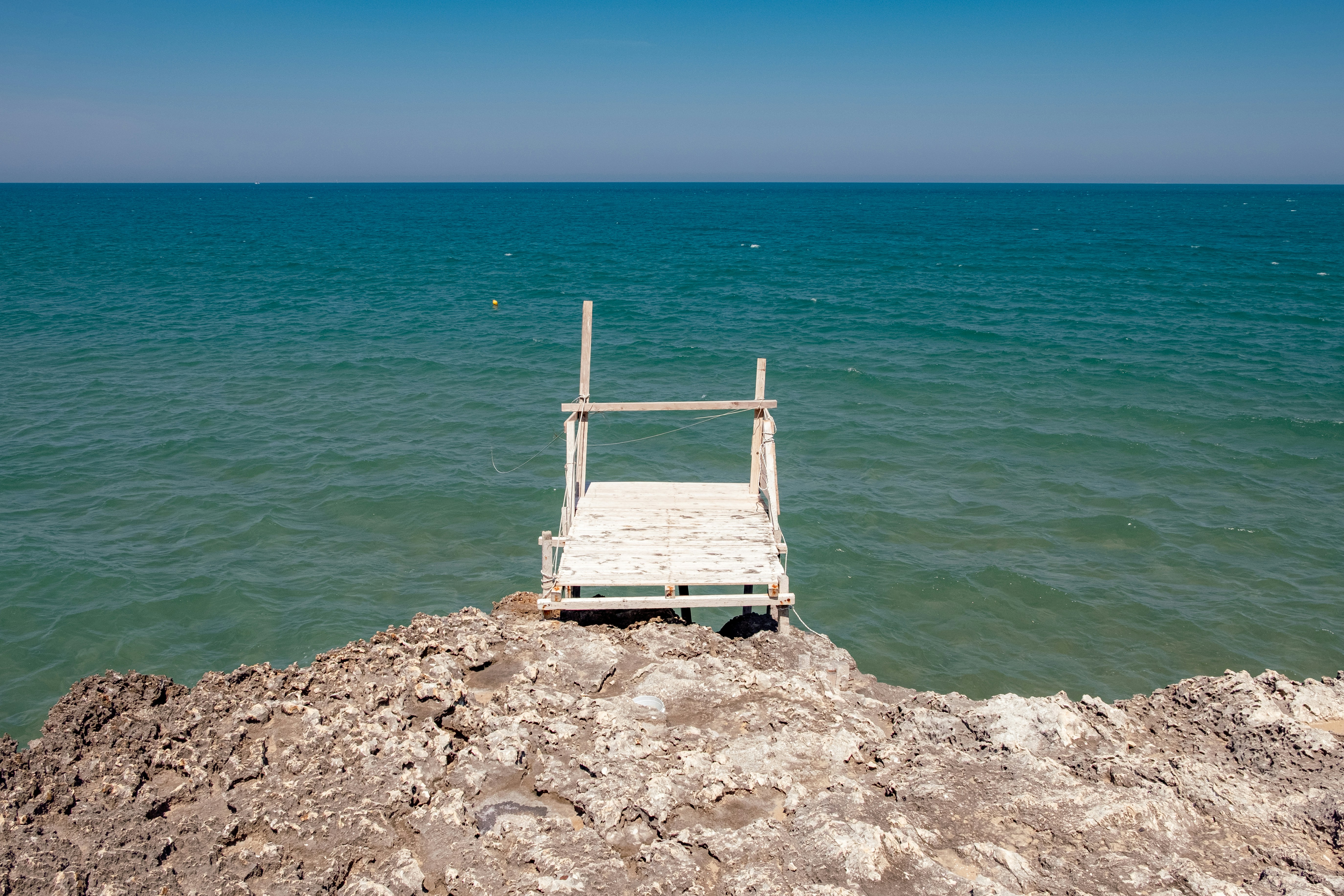 Diving board on rocky cliff overlooking blue ocean
