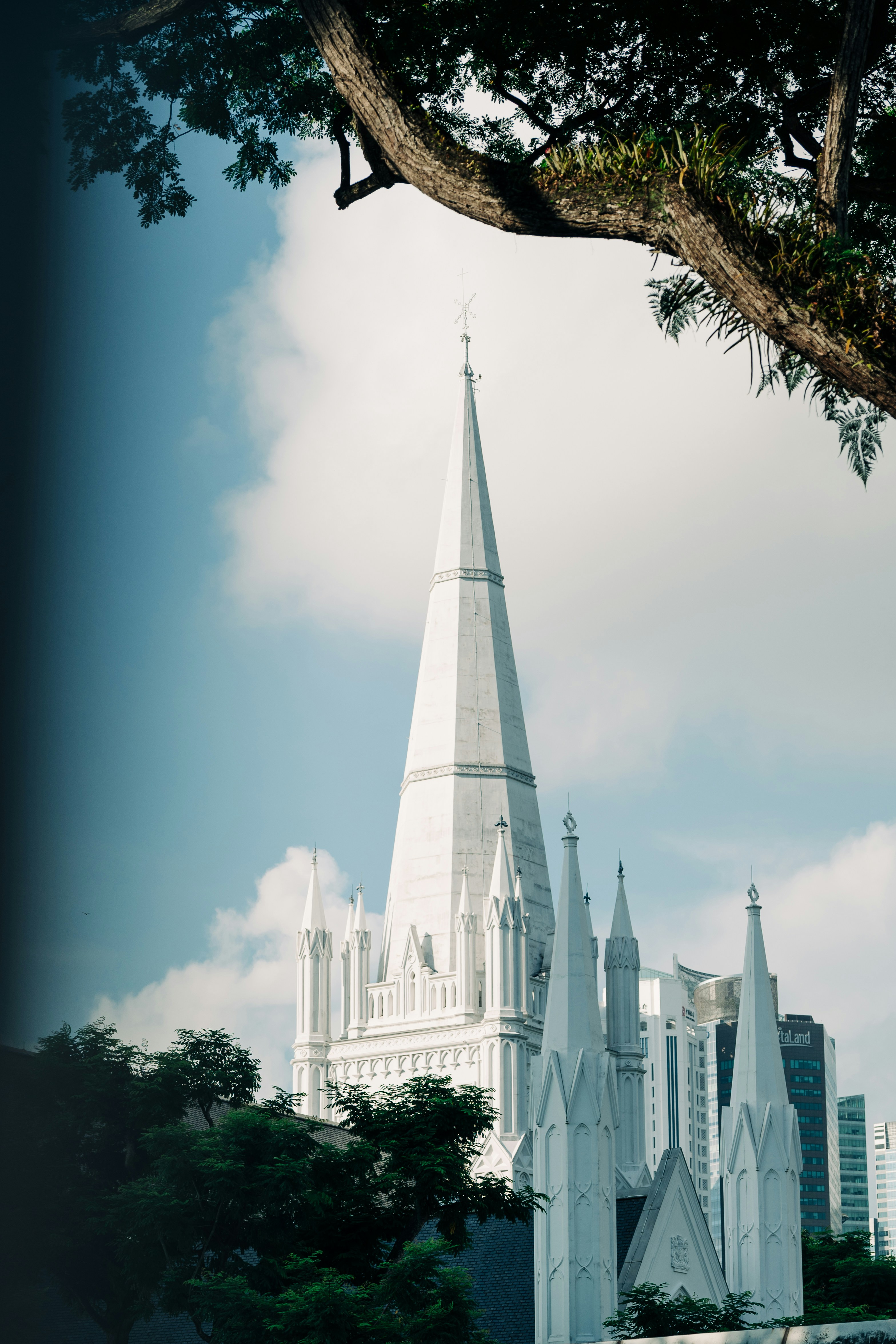 Tall white church steeple under a blue sky with clouds