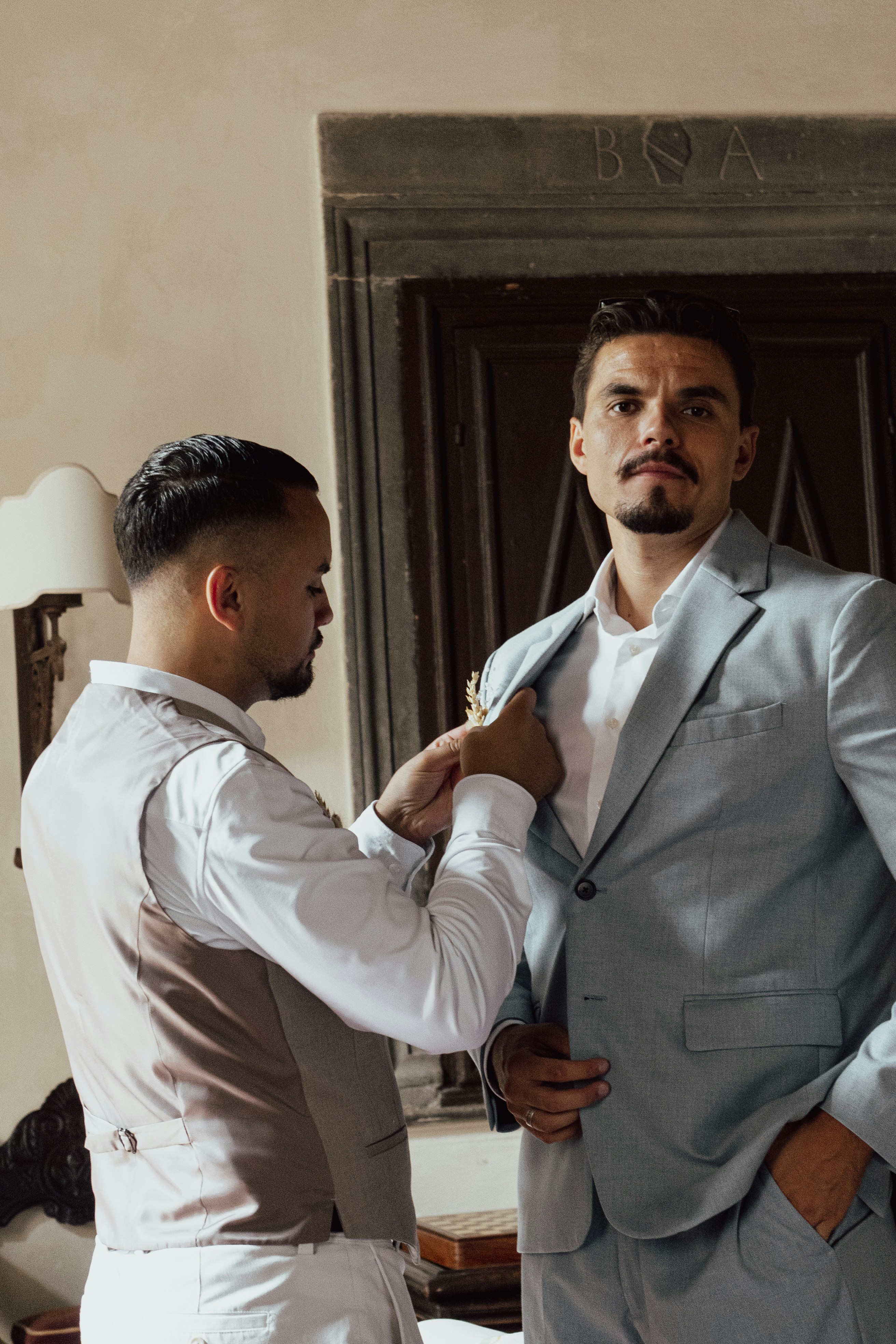 Man in vest adjusting another man's light blue suit