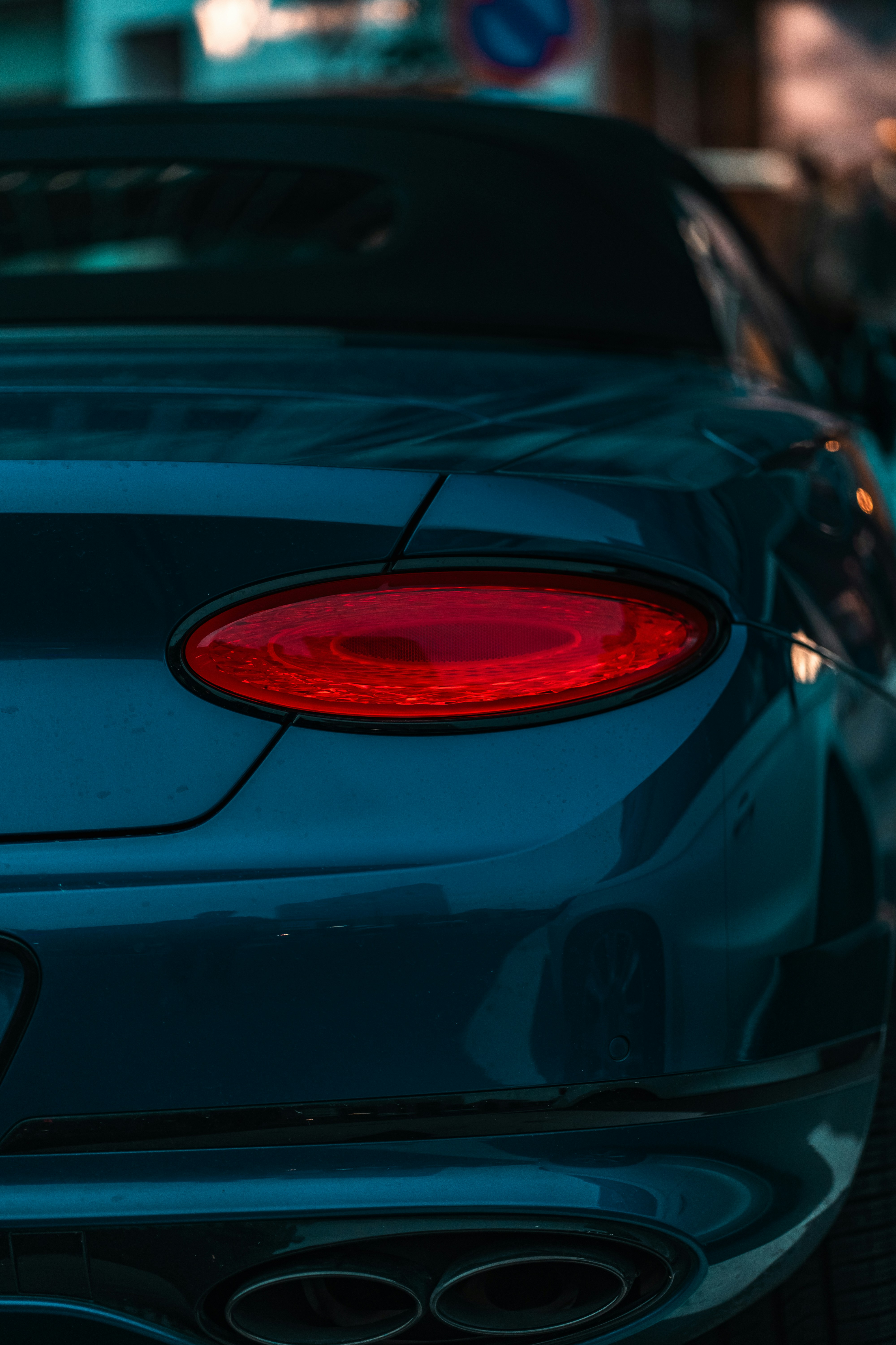 Dark blue car's rear with glowing red taillight