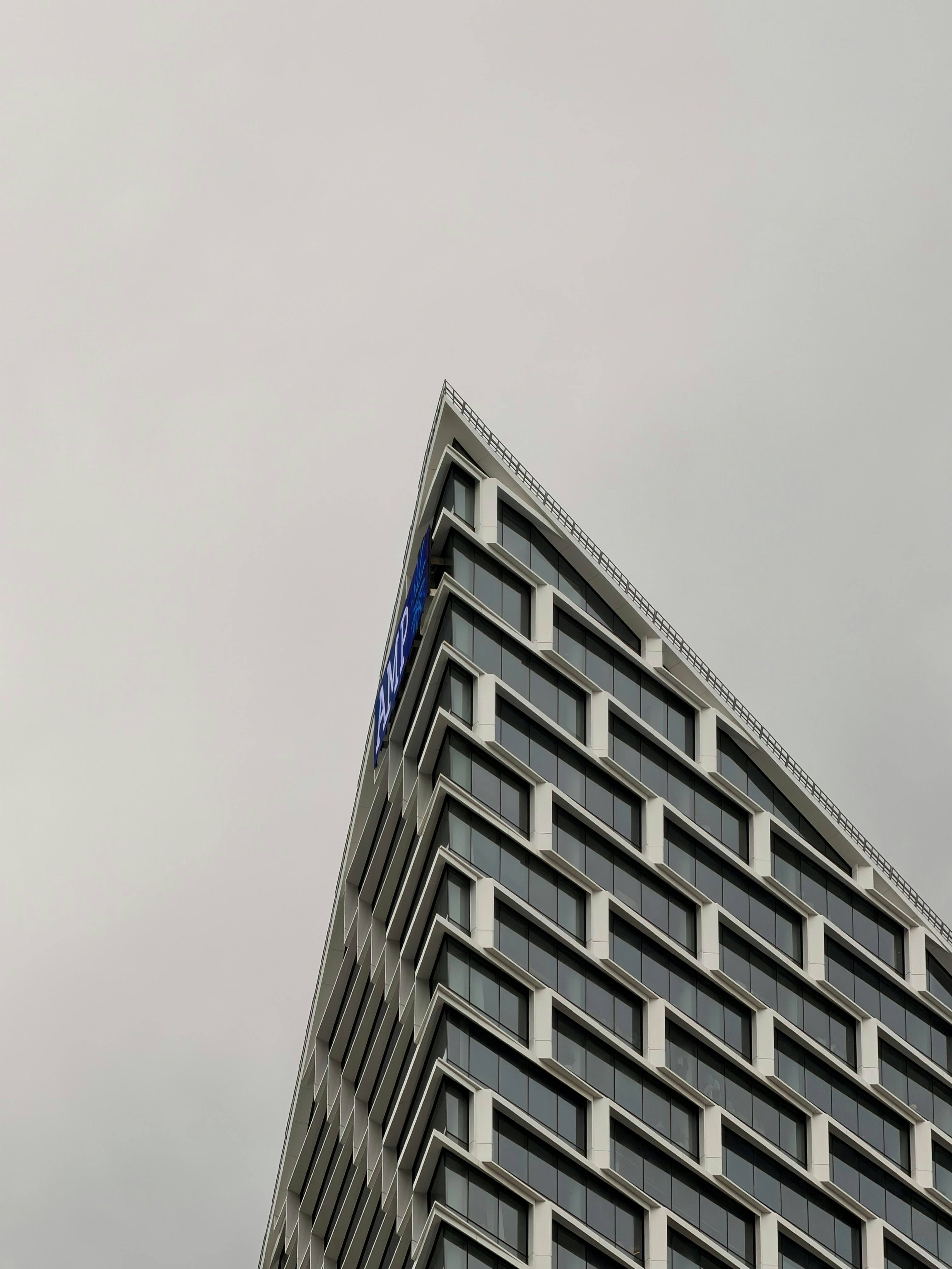 Triangular modern building facade against an overcast sky.