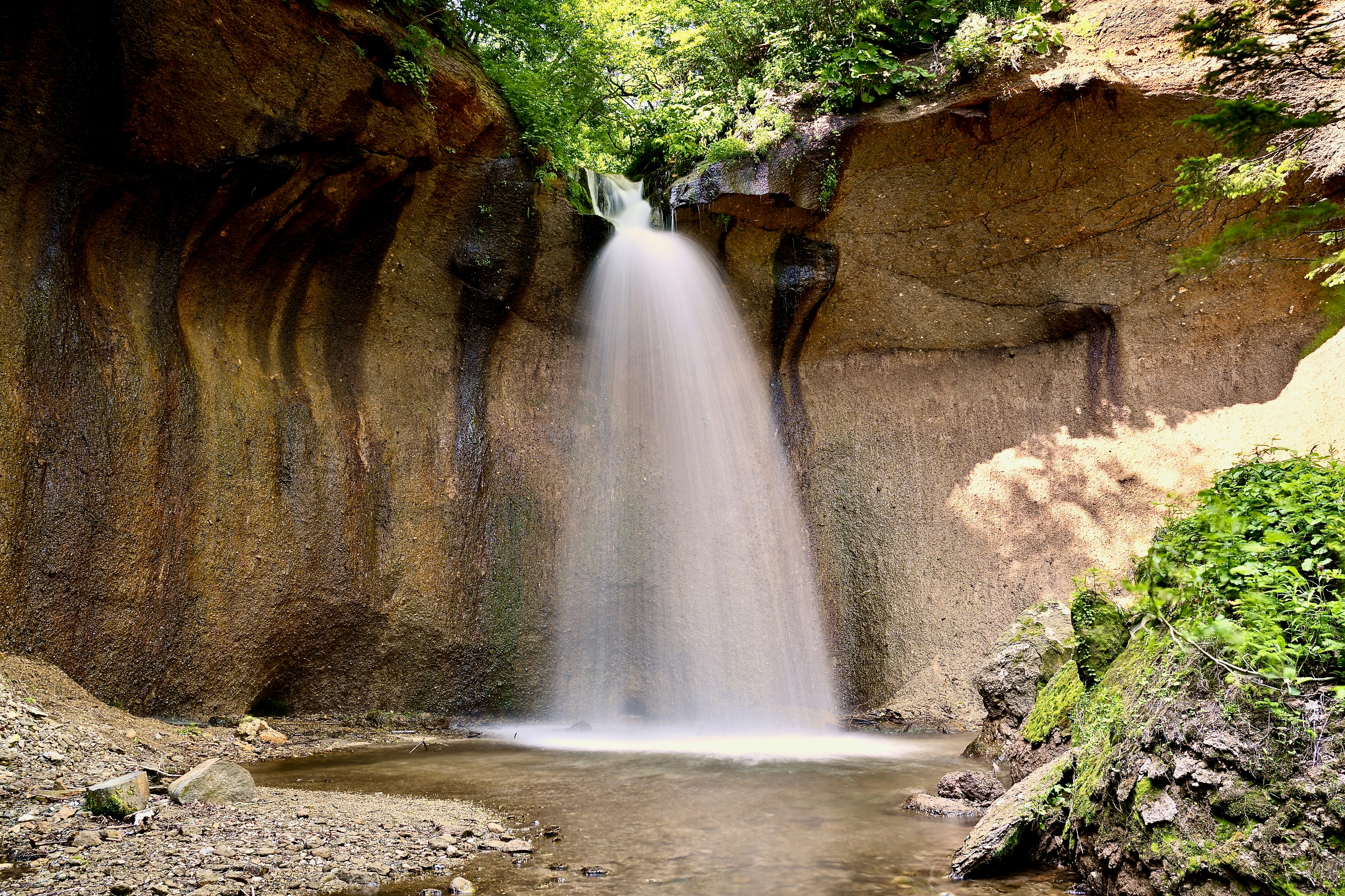 Serene waterfall flowing into a pool surrounded by rocky cliffs.