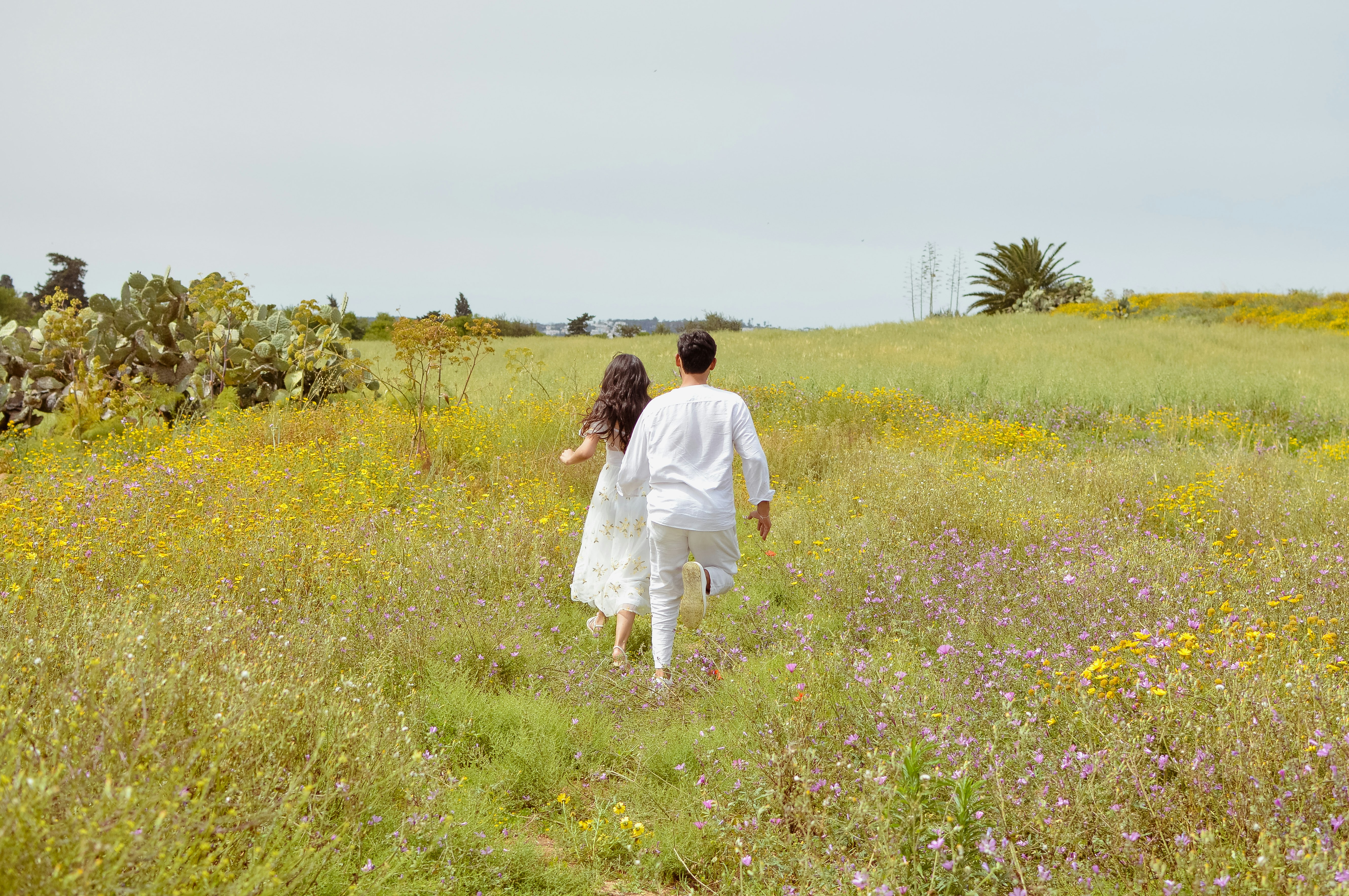 Two people running through a field of wildflowers