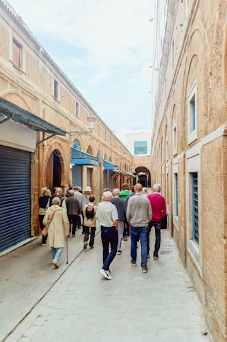 People walking down a narrow street between old buildings.