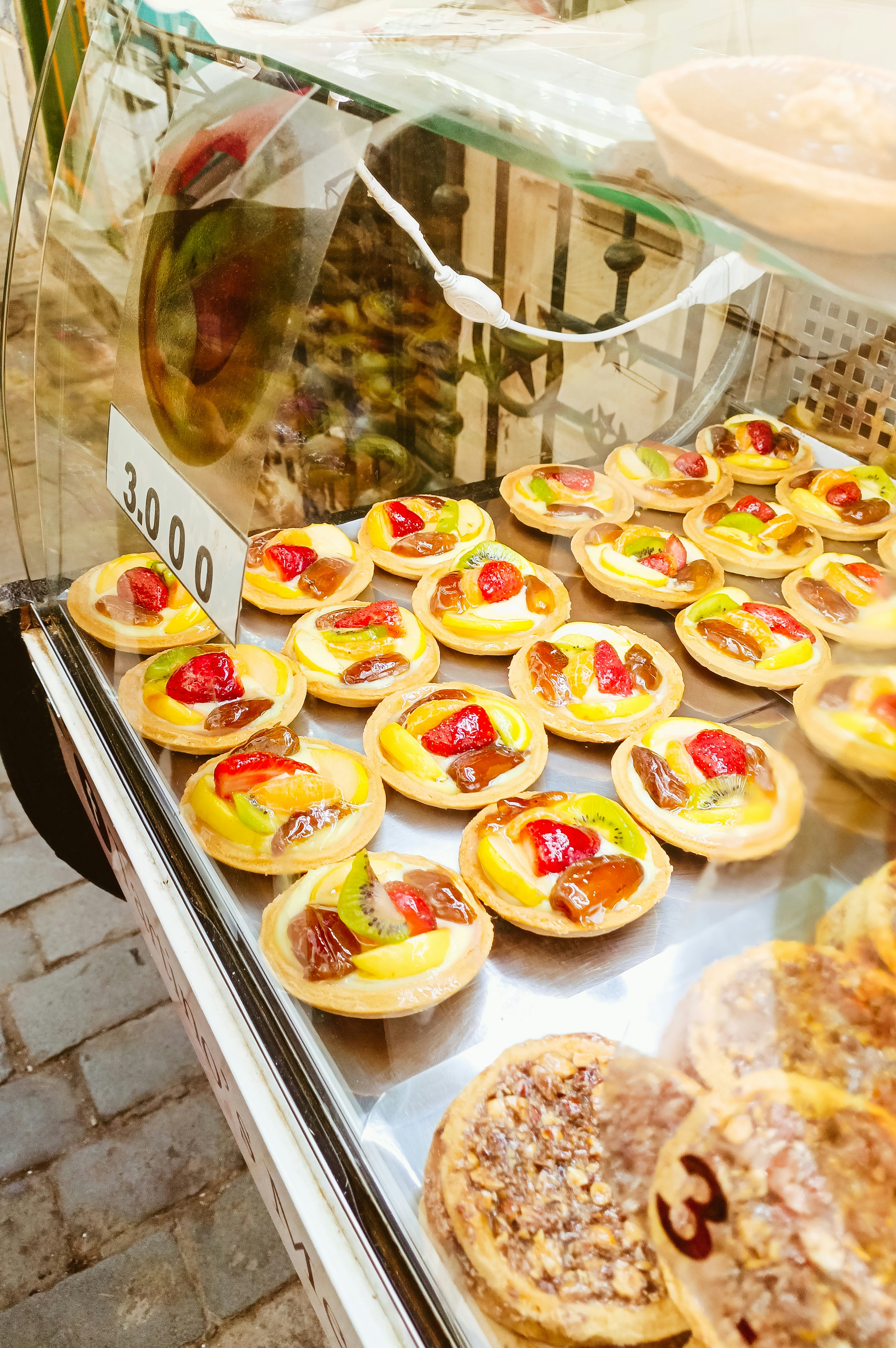 Bunte Obsttörtchen und Gebäck in einer Bäckerei präsentiert.