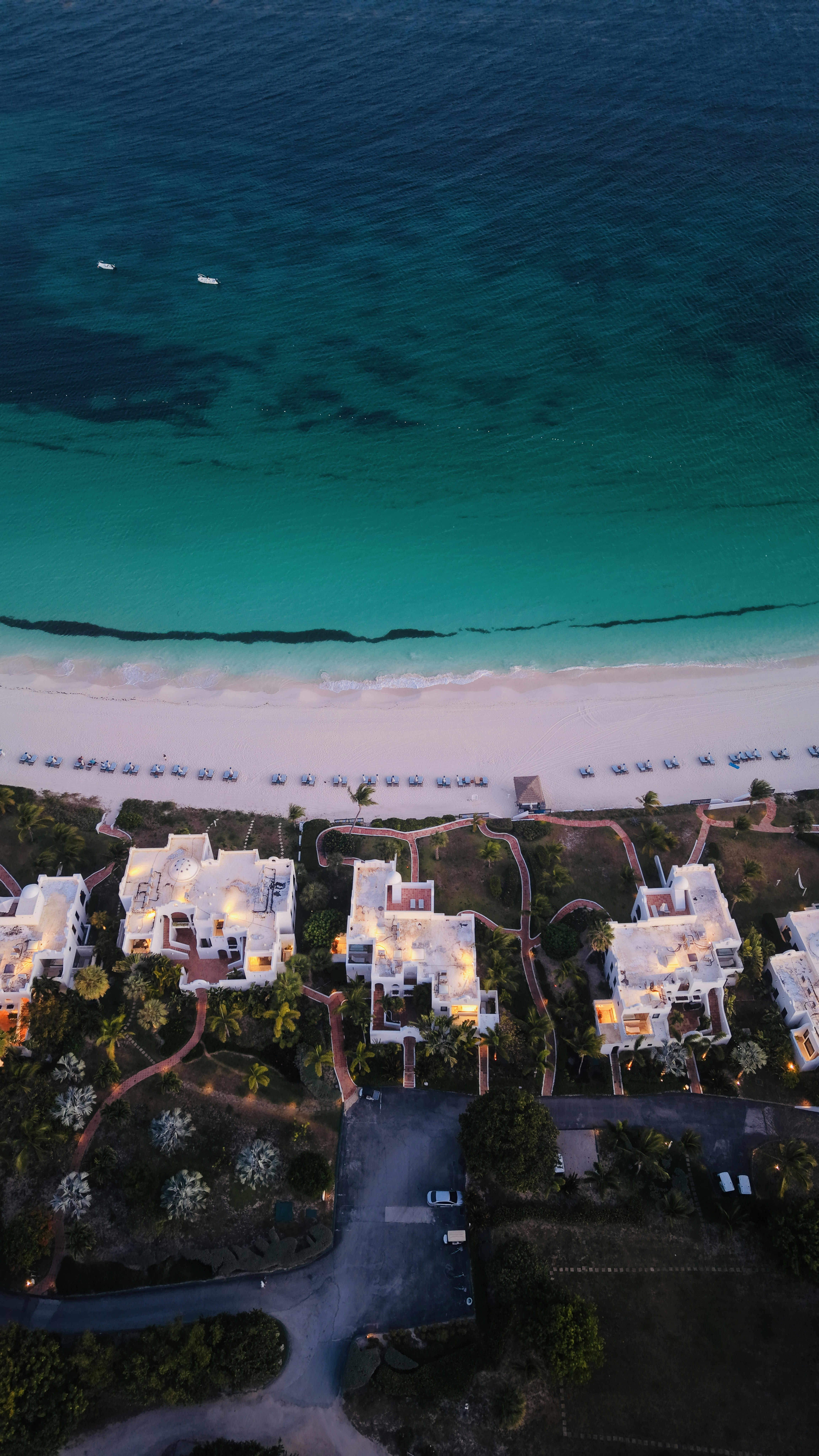 White villas line a turquoise beach at dusk.