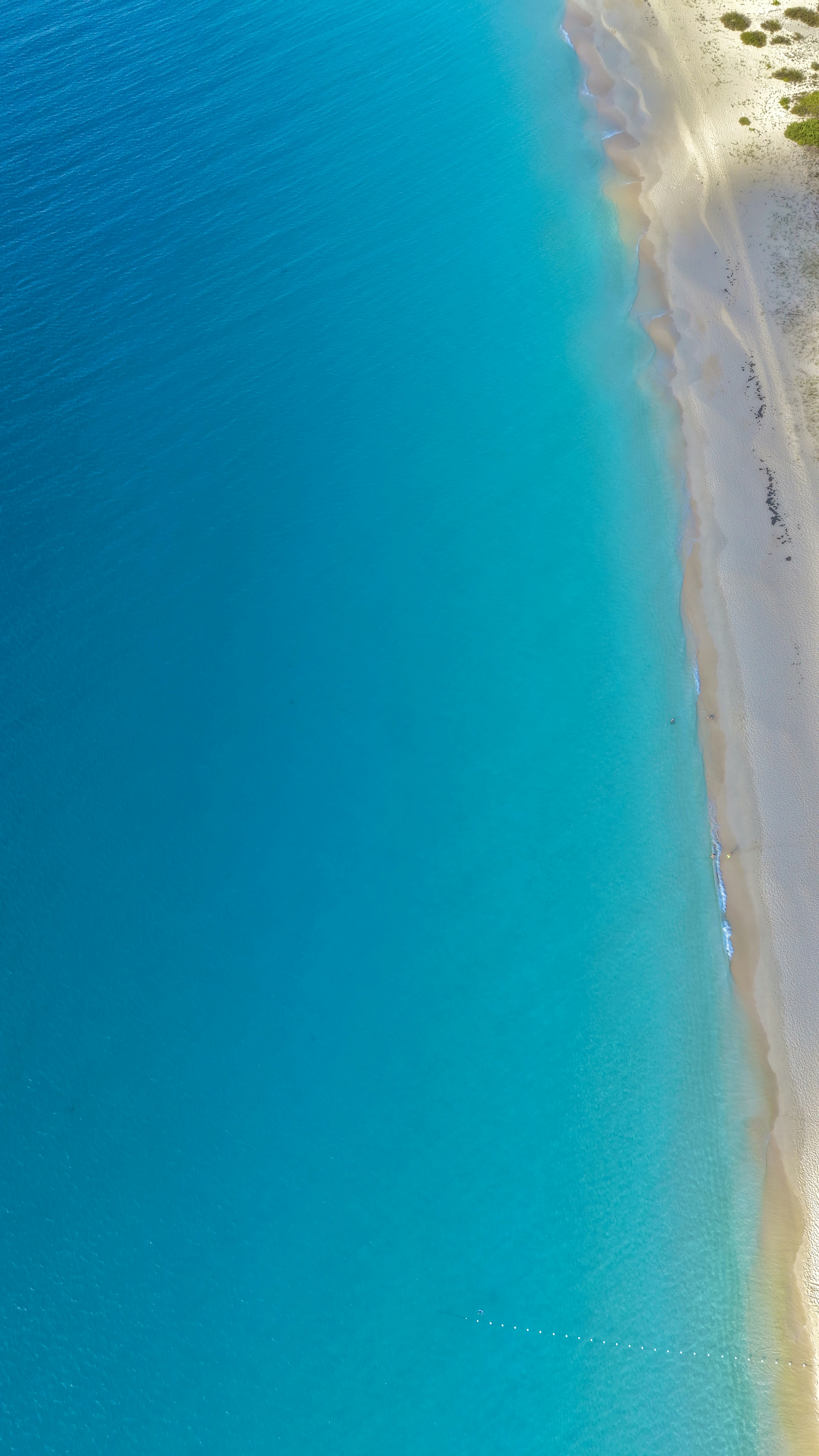 Aerial view of turquoise ocean meeting a sandy beach.