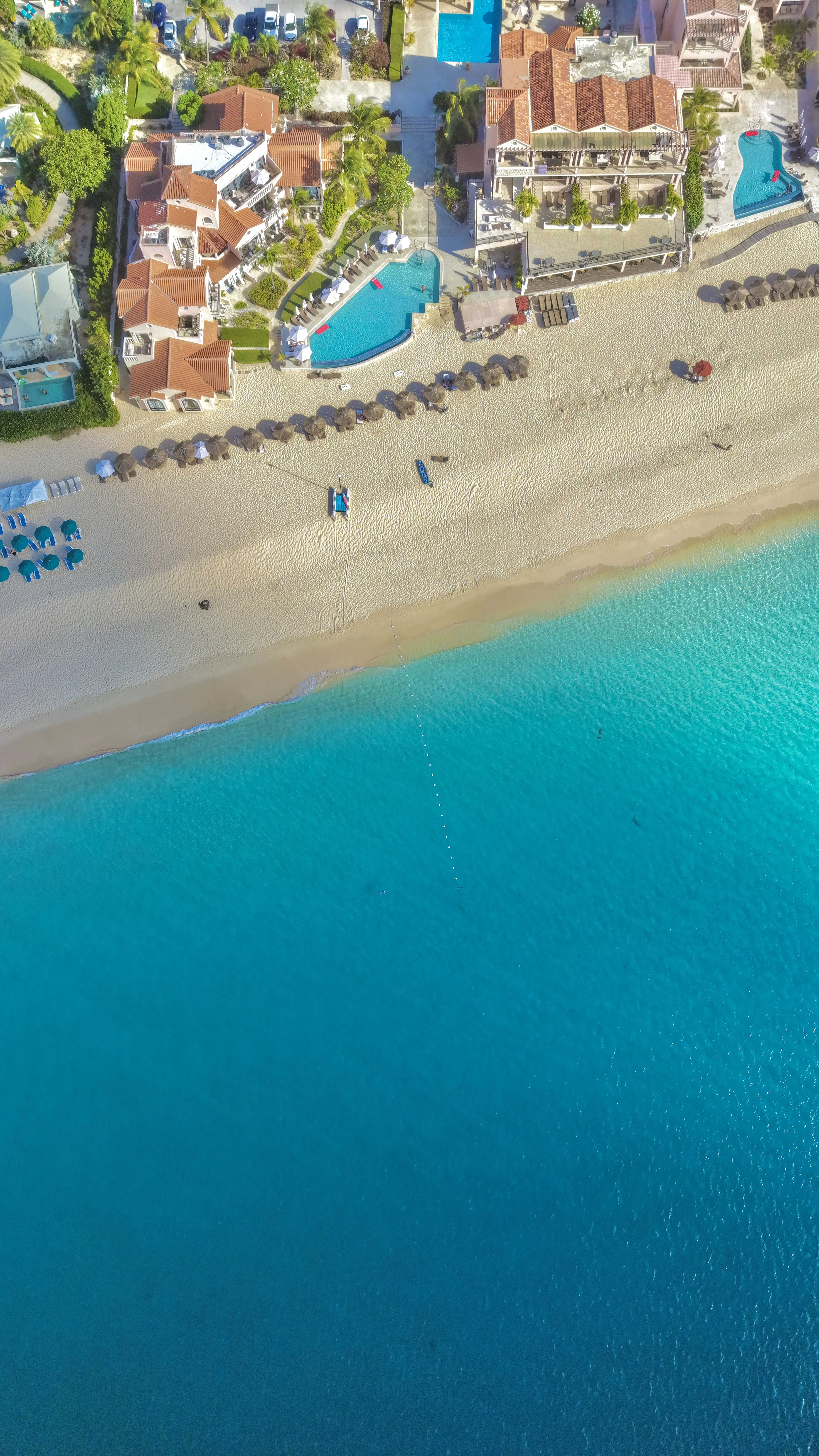 Aerial view of luxury beach resorts, turquoise ocean, and pools.