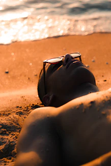 A man relaxing on a sandy beach at sunset.