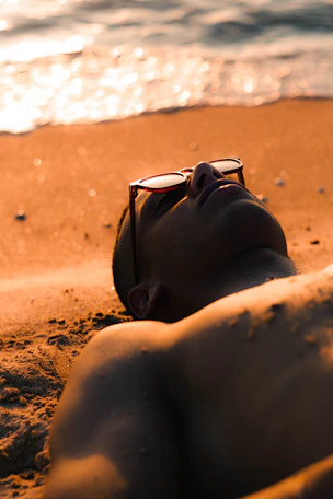 A man relaxing on a sandy beach at sunset.