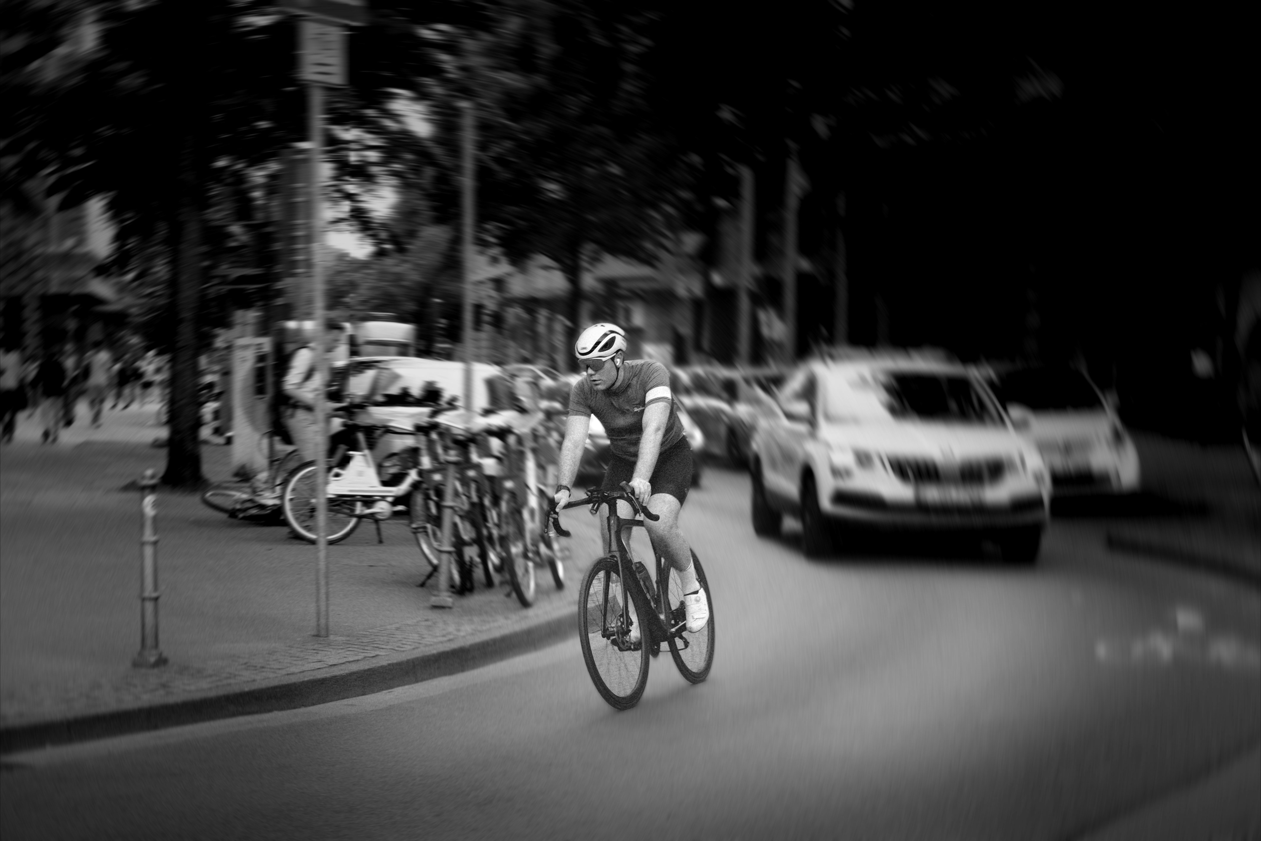 Black and white cyclist riding past parked cars
