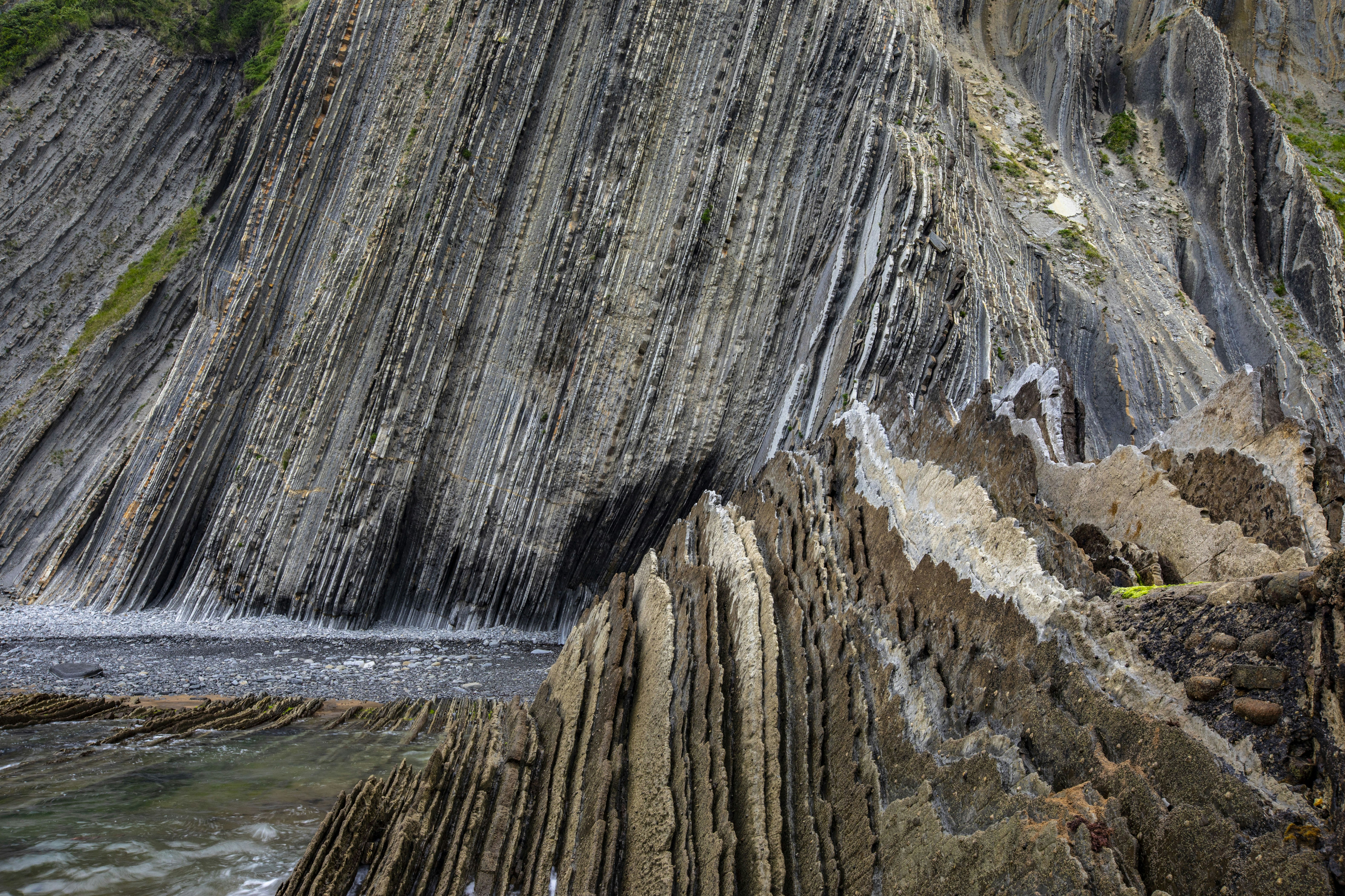 Dramatic layered rock formations along a rugged coastline.