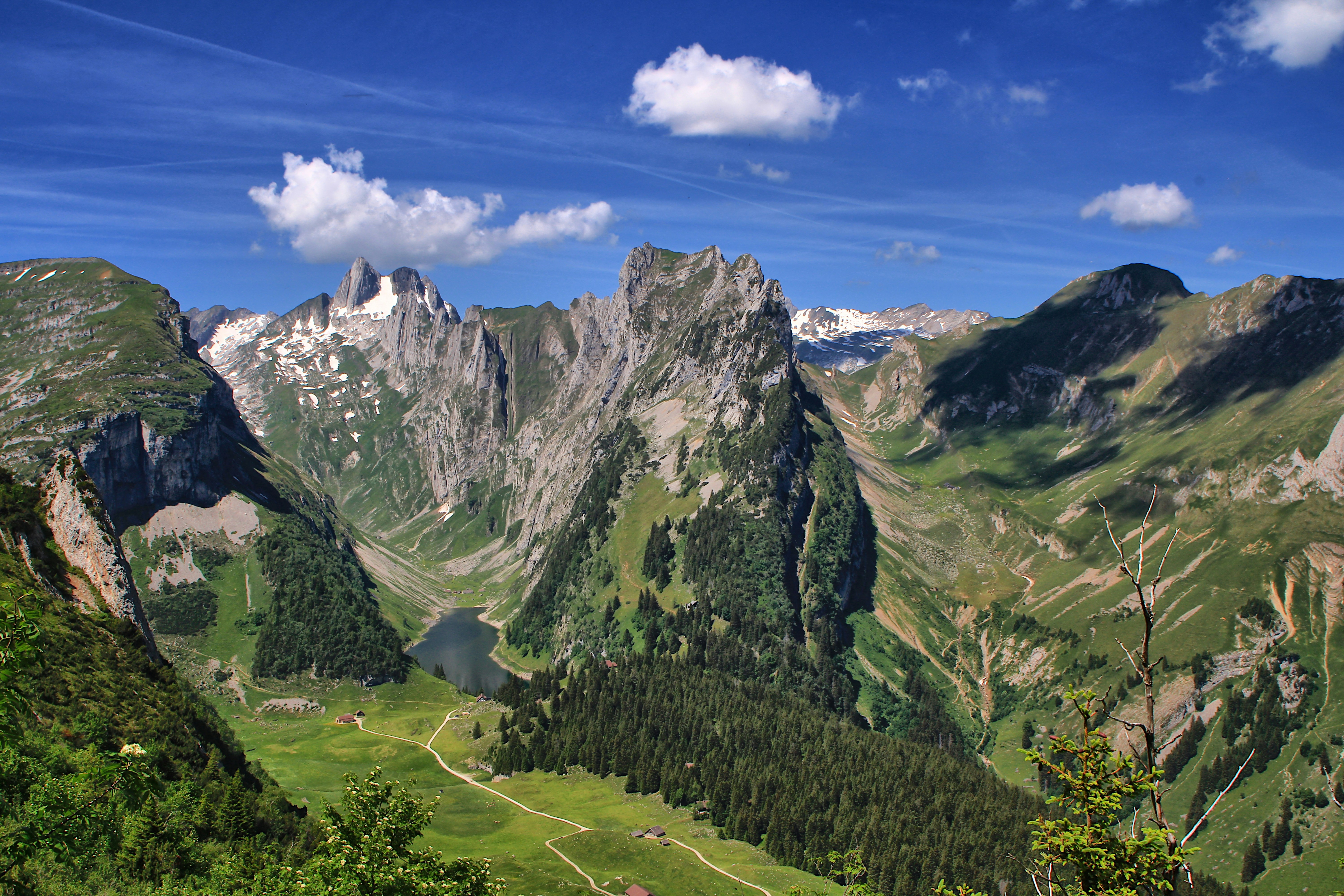 Majestic mountain landscape with a green valley and small lake.