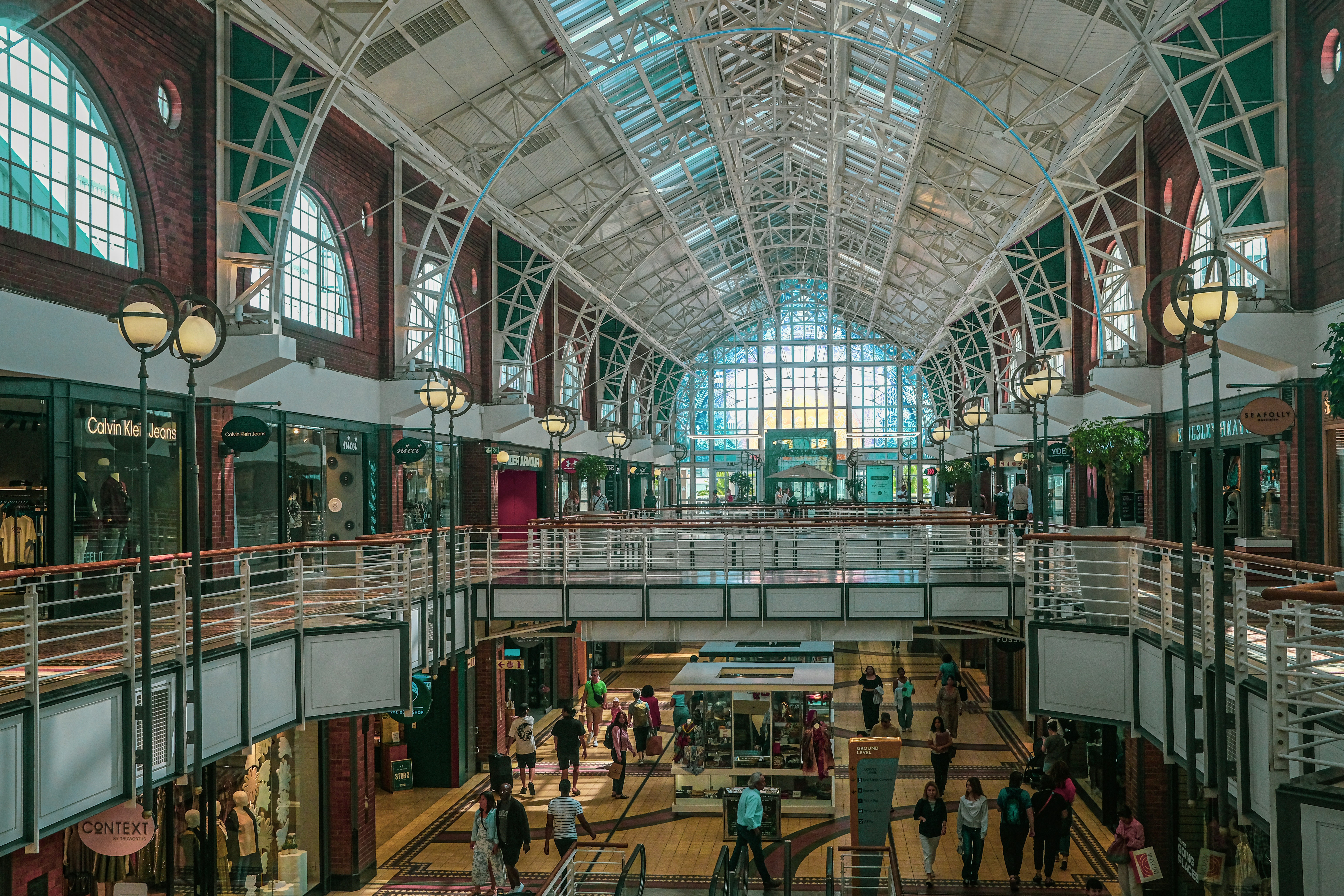 People walking through a large, multi-level indoor shopping mall.