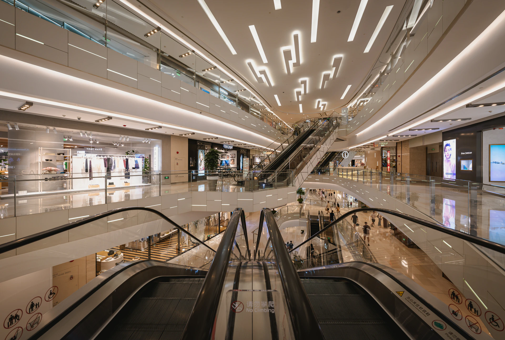 Brightly lit modern shopping mall with multiple escalators