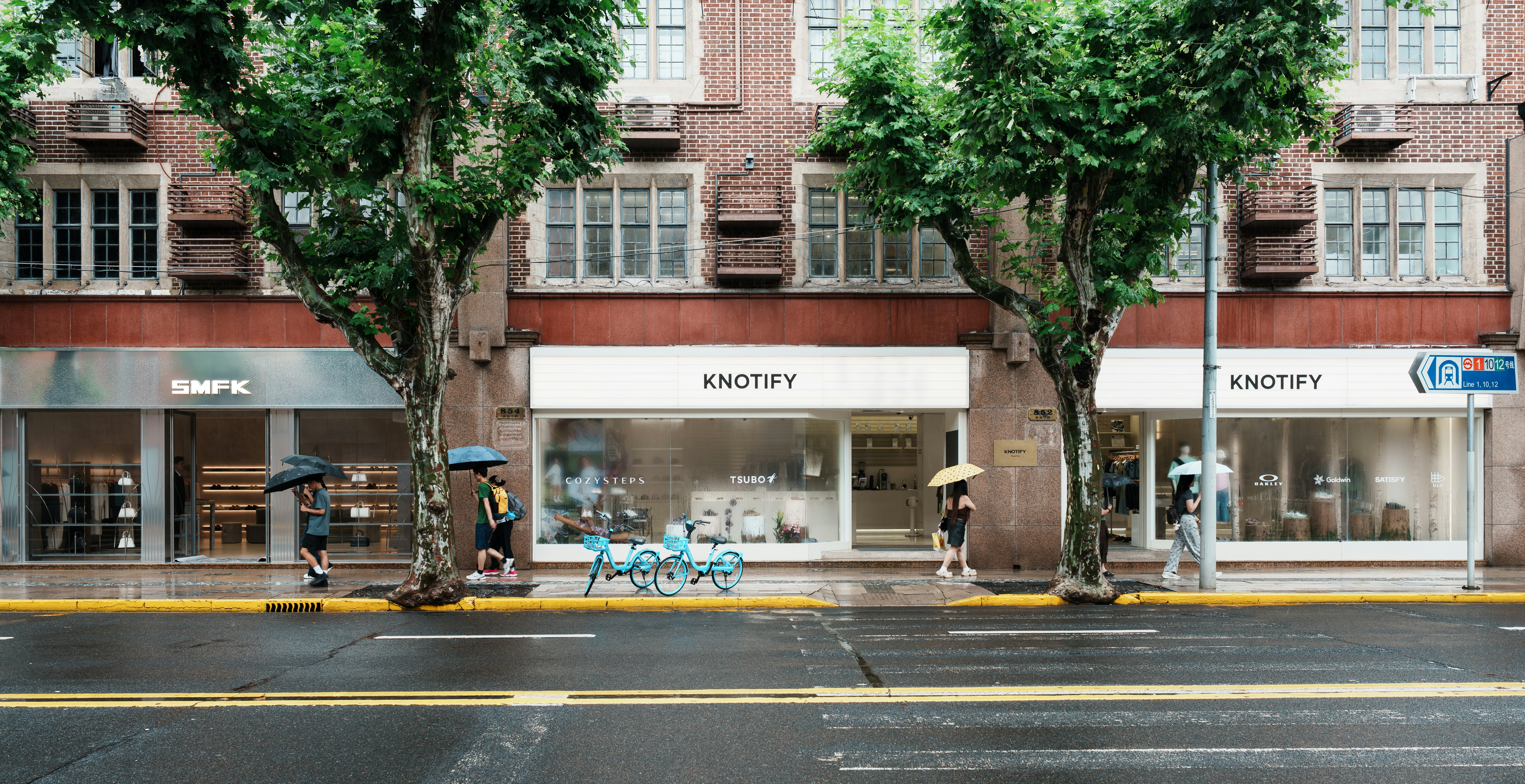 Storefronts and trees along a wet city street